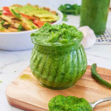 Green color coriander chutney in a glass bottle.