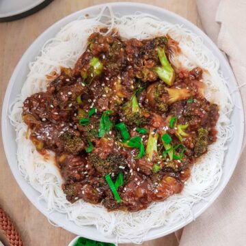 Broccoli with garlic sauce served on white rice noodles and topped with spring onions