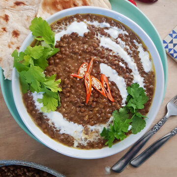 Lentil Curry in white bowl served with garlic naan