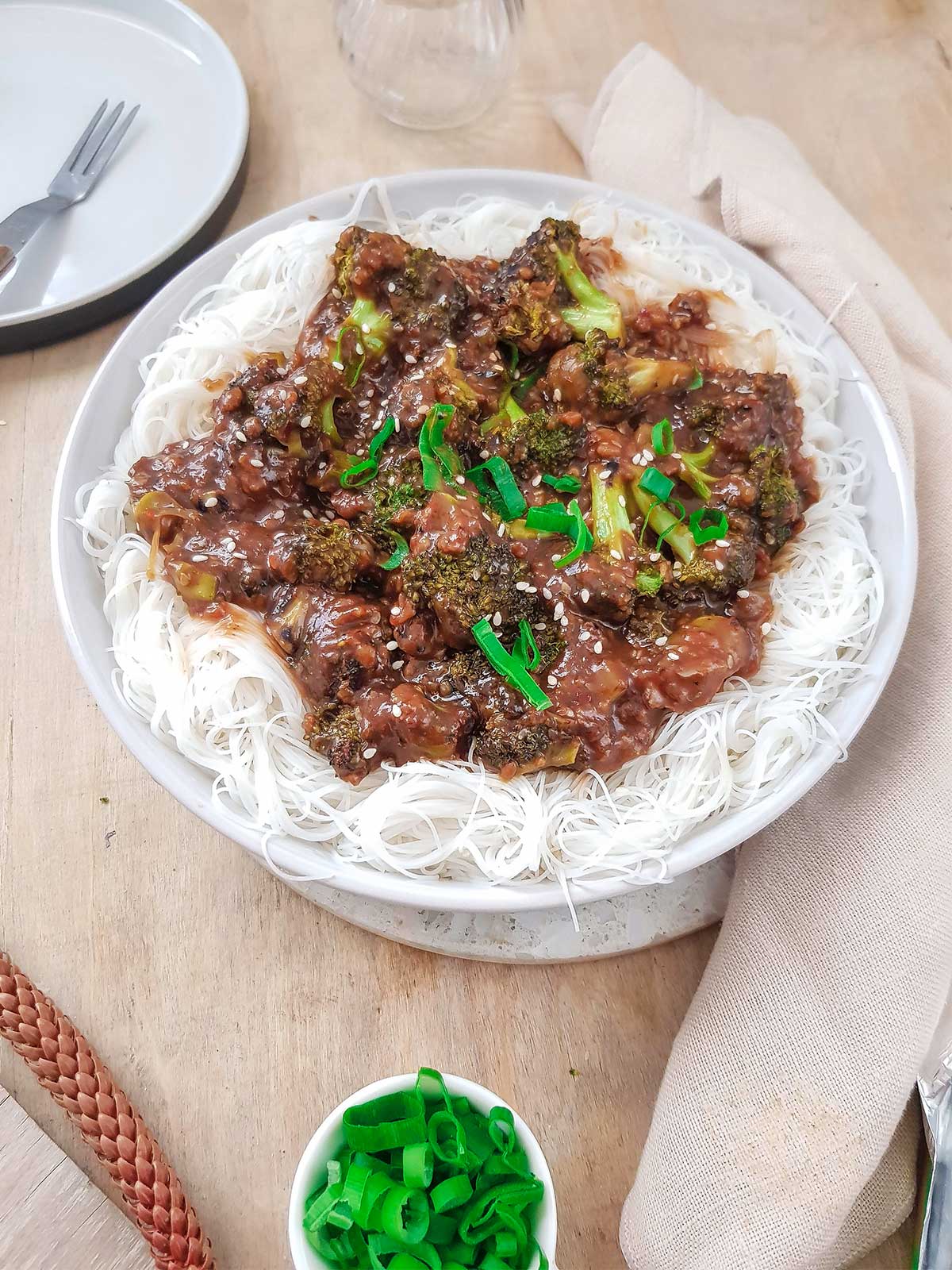 Broccoli with garlic sauce served on white rice noodles topped with spring onions