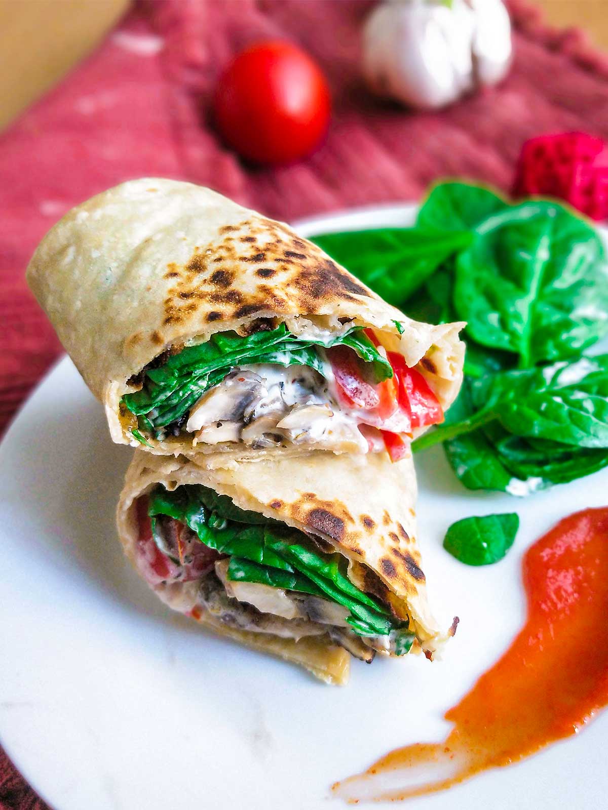 Mushroom wrap cut in half served on white plate with red ketchup 