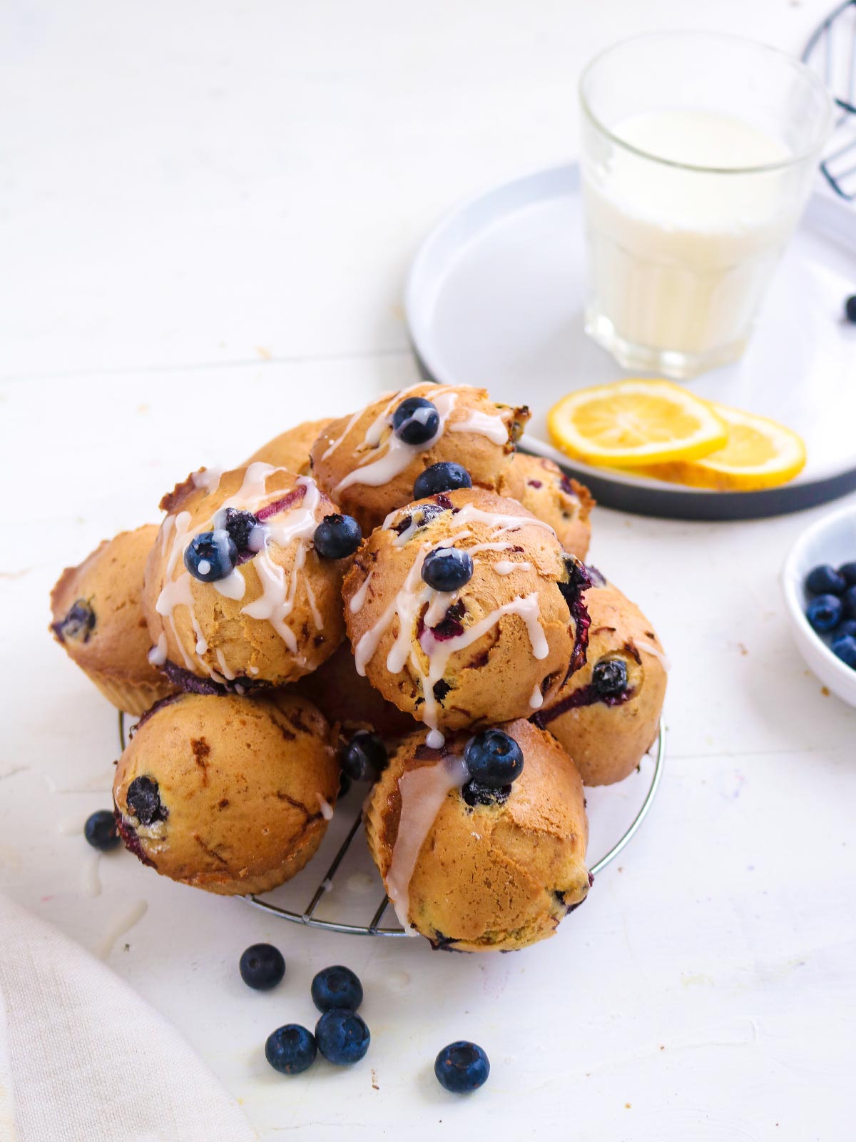 Vegan Blueberry lemon muffins topped with sugar lemon glaze. stack on a wire rack .