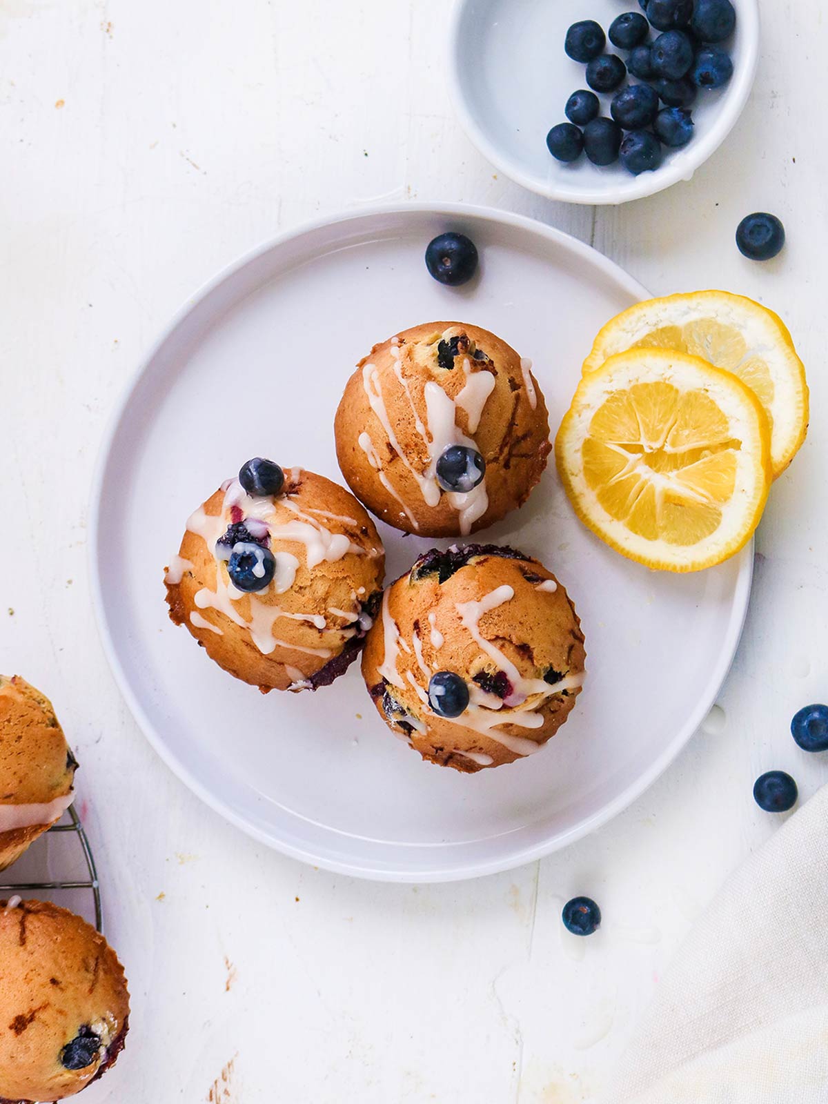 Vegan Blueberry lemon muffins served on top with lemon slices on side.