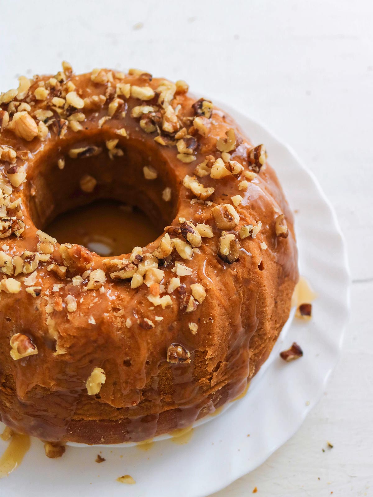 Vegan pumpkin bundt cake topped with caramel glaze and chopped walnuts