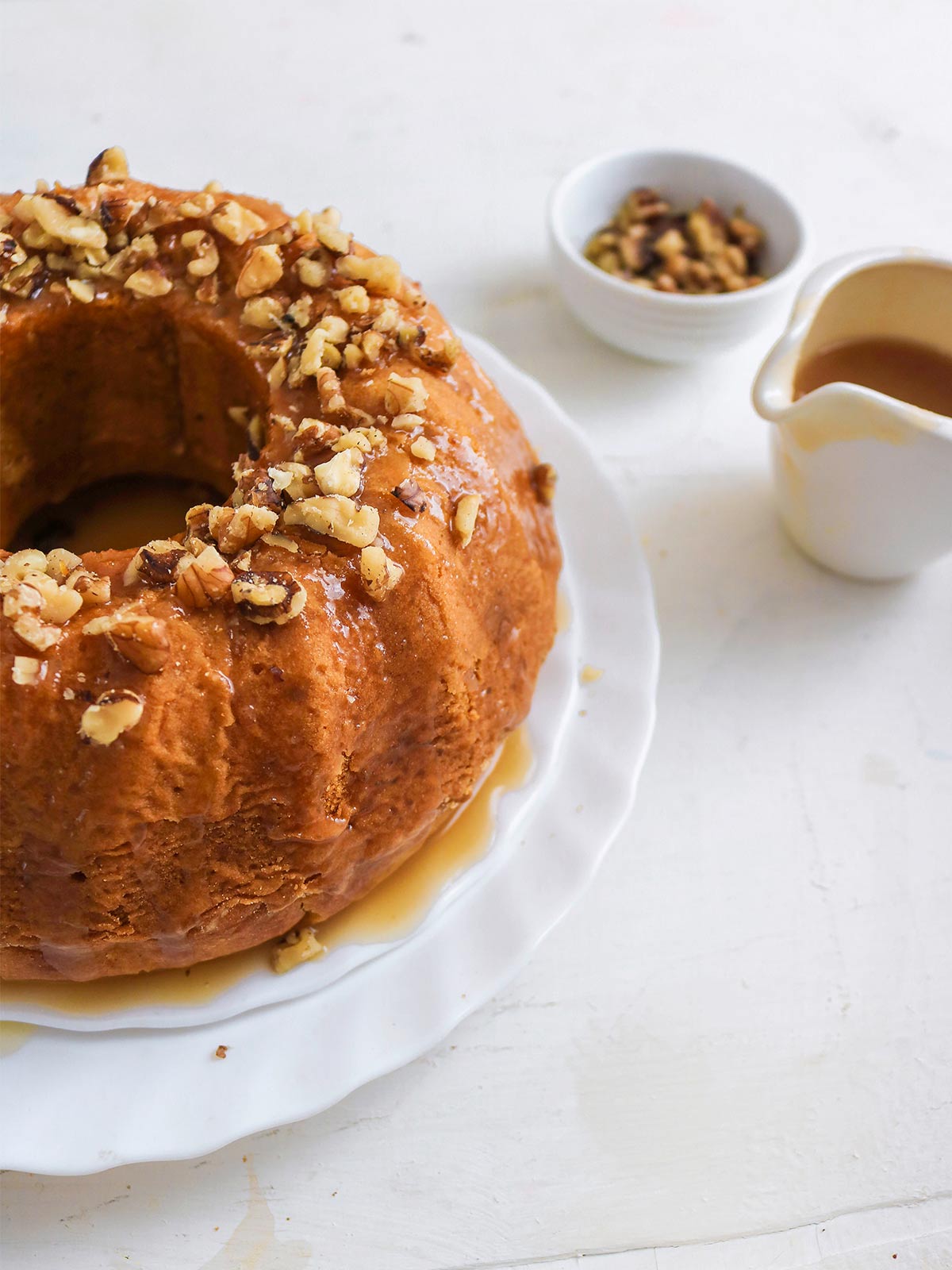 Vegan pumpkin bundt cake topped with caramel glaze and chopped walnuts