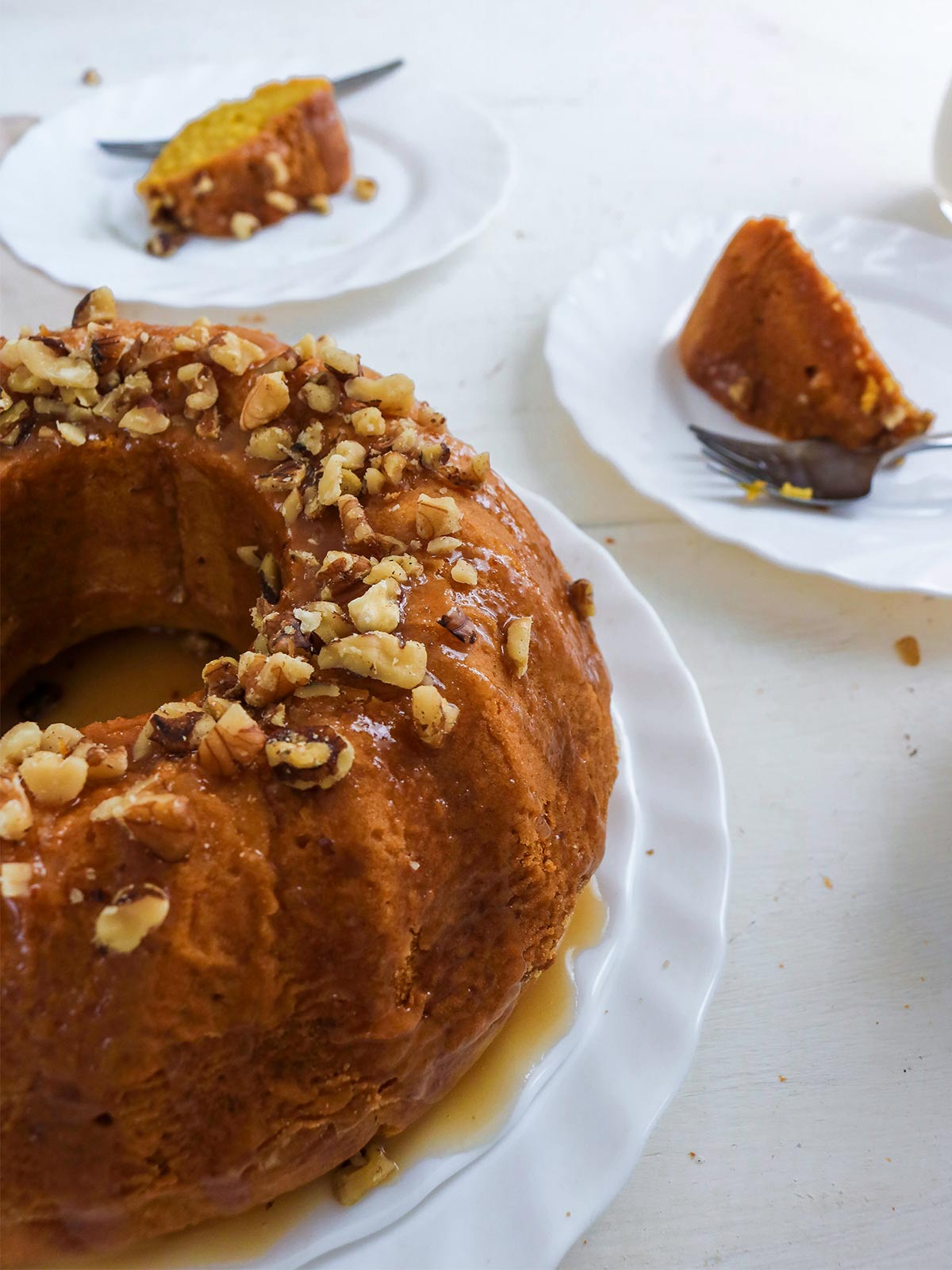 Vegan pumpkin bundt cake topped with caramel glaze and chopped walnuts