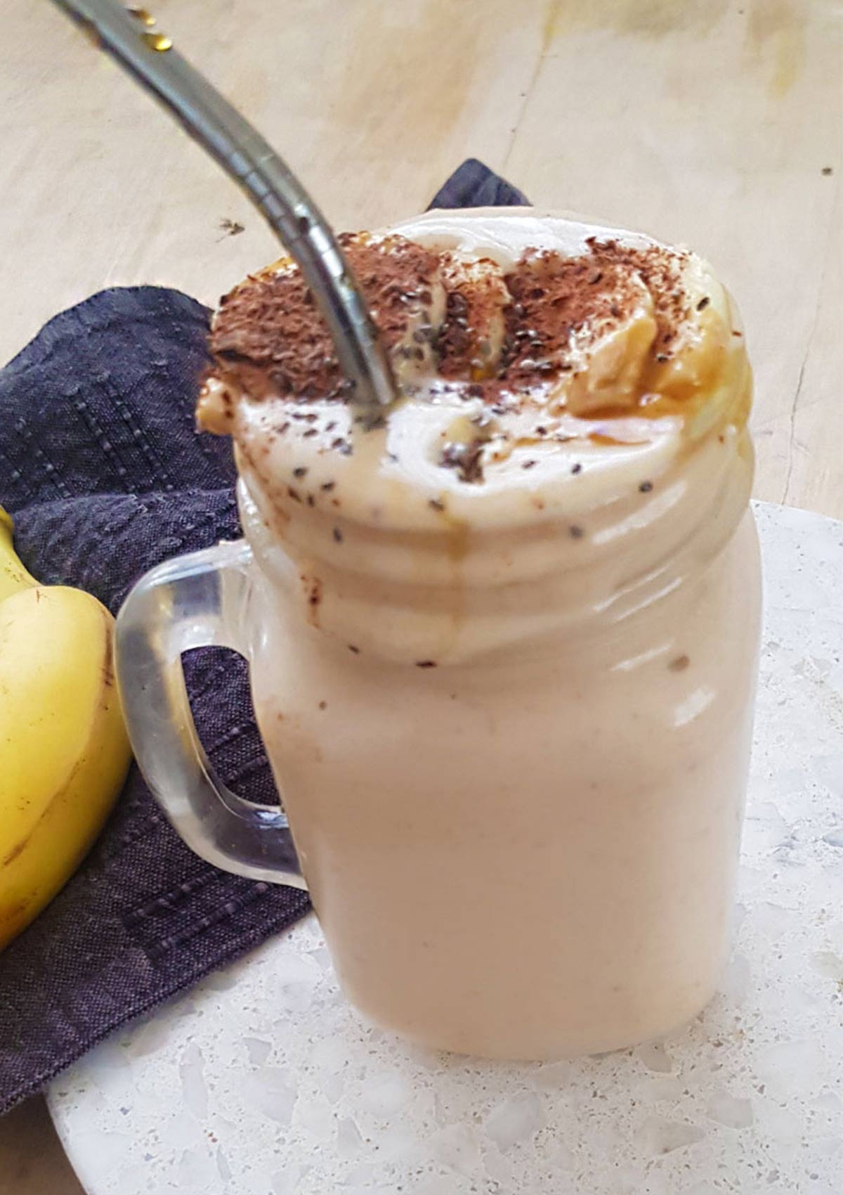 peanut butter banana smoothie in a glass jar with metal straw