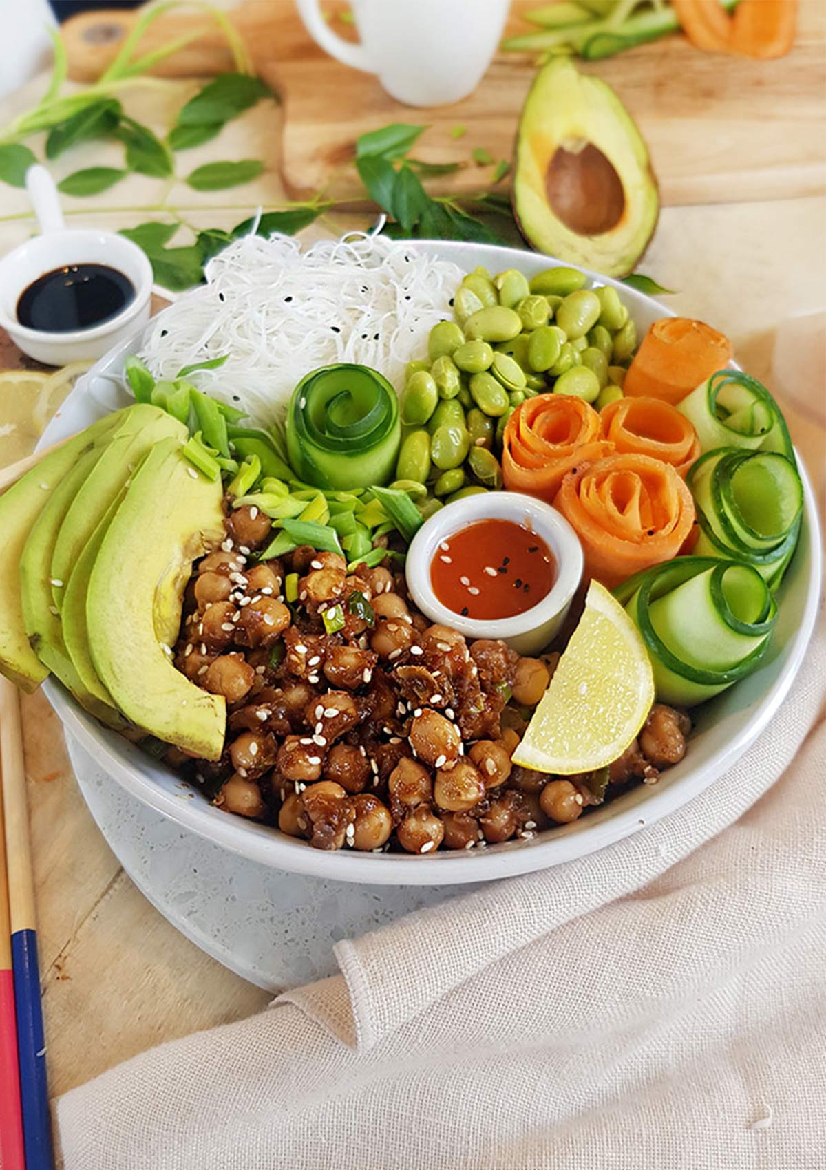 poke bowl of chickpeas with carrot and cucumber rolls , edamame , avocado and rice noodles. 