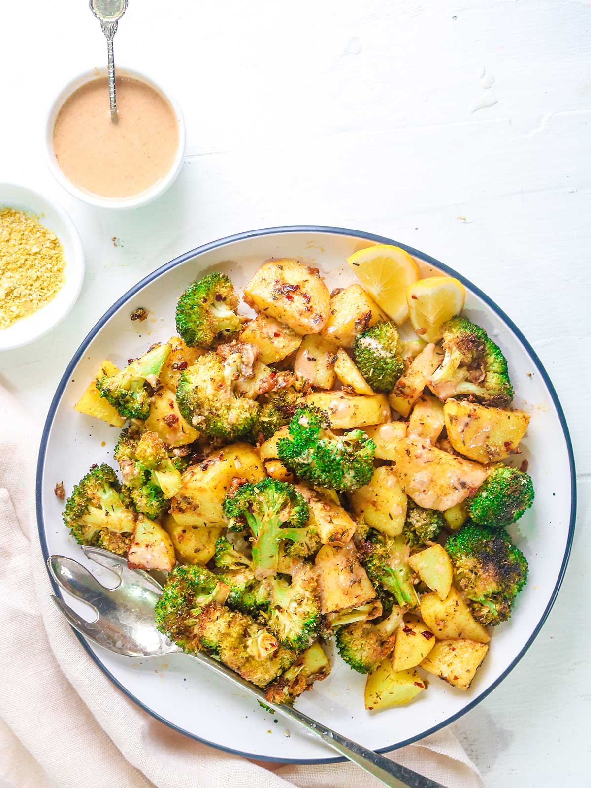 Roasted broccoli and potatoes served in a white plate with fork