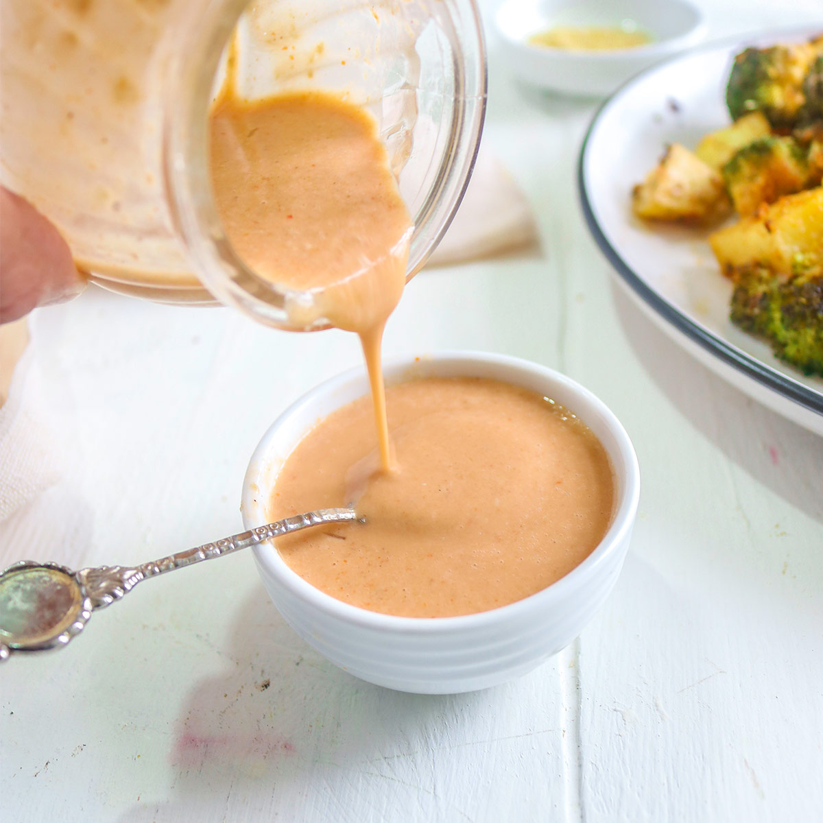 Pouring spicy tahini sauce in a bowl