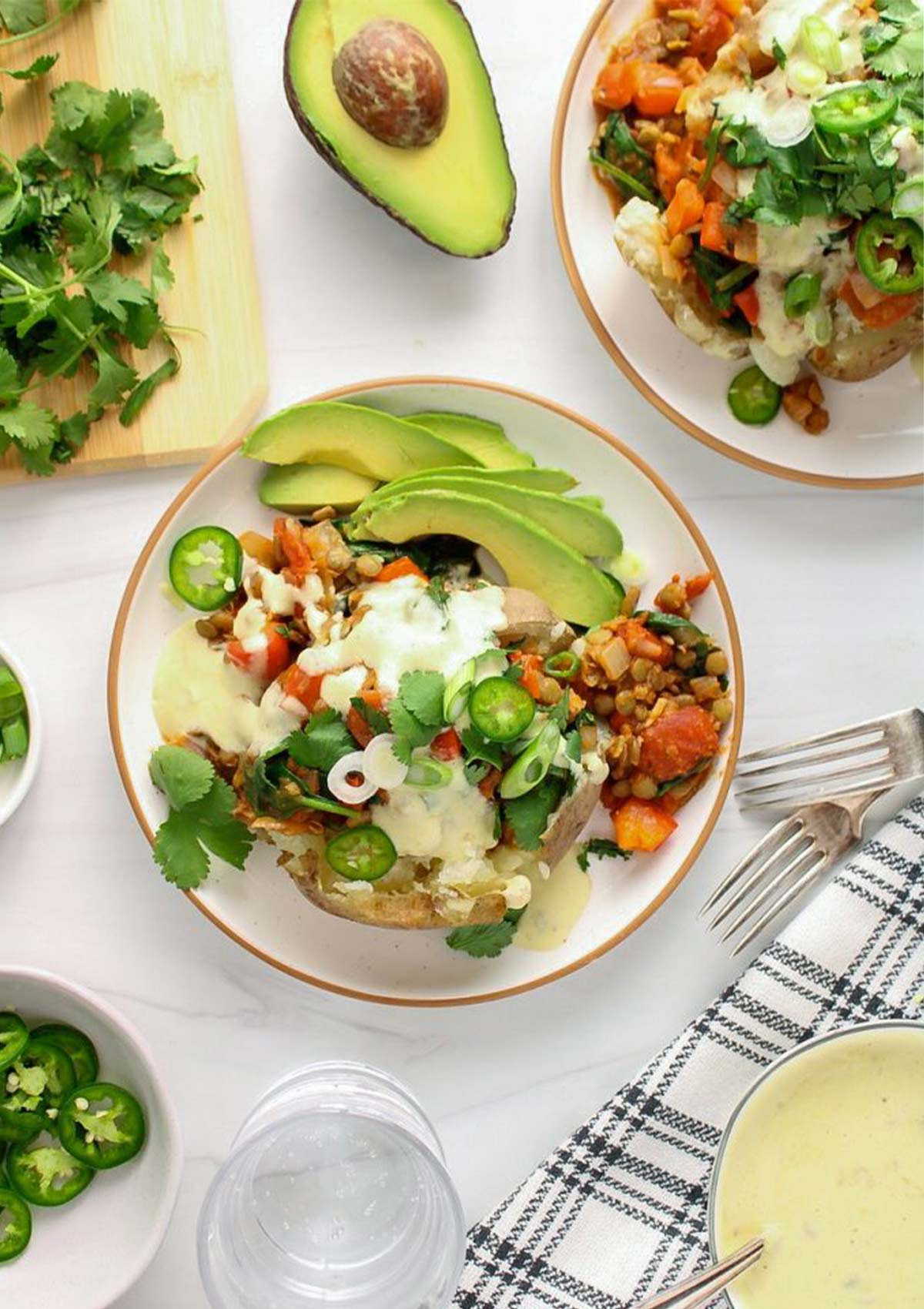 Mexican baked potato served in plate toped with veggies and avocado 