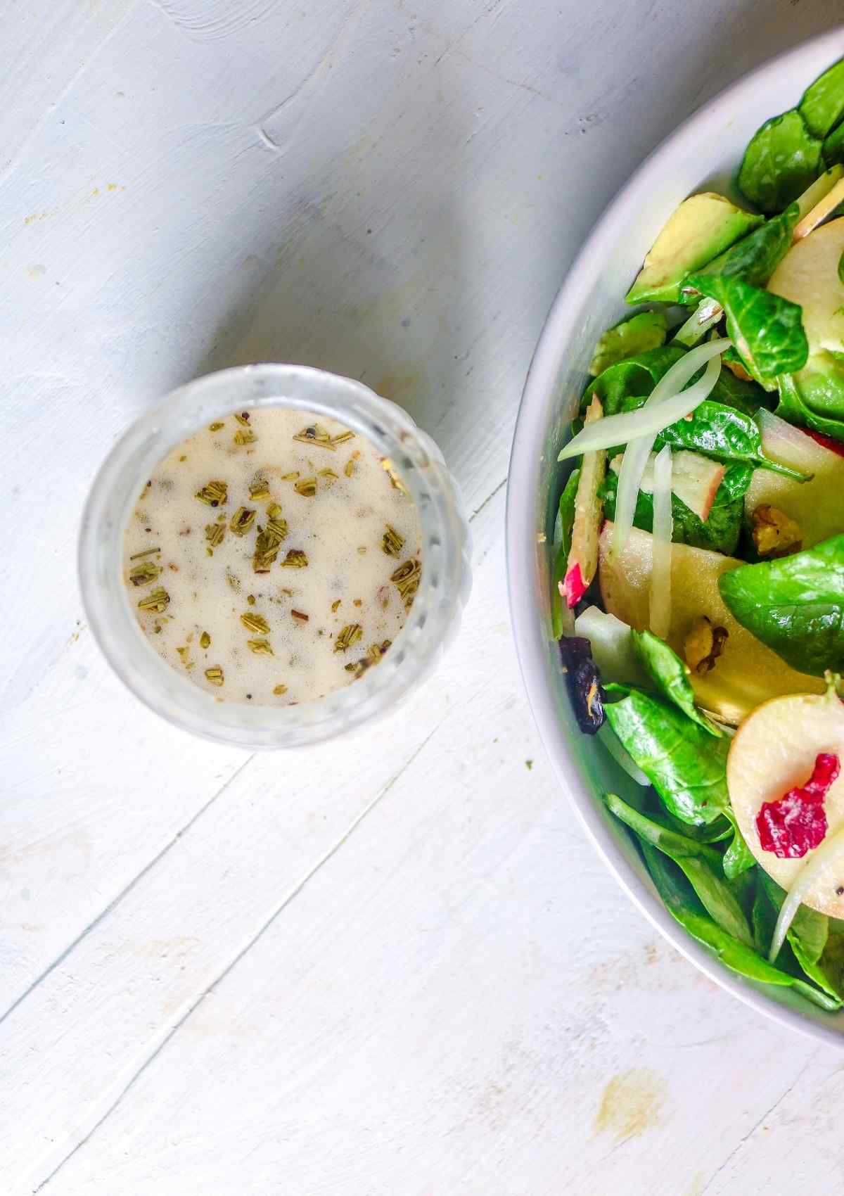 salad dressing with a bowl of vegan spinach salad