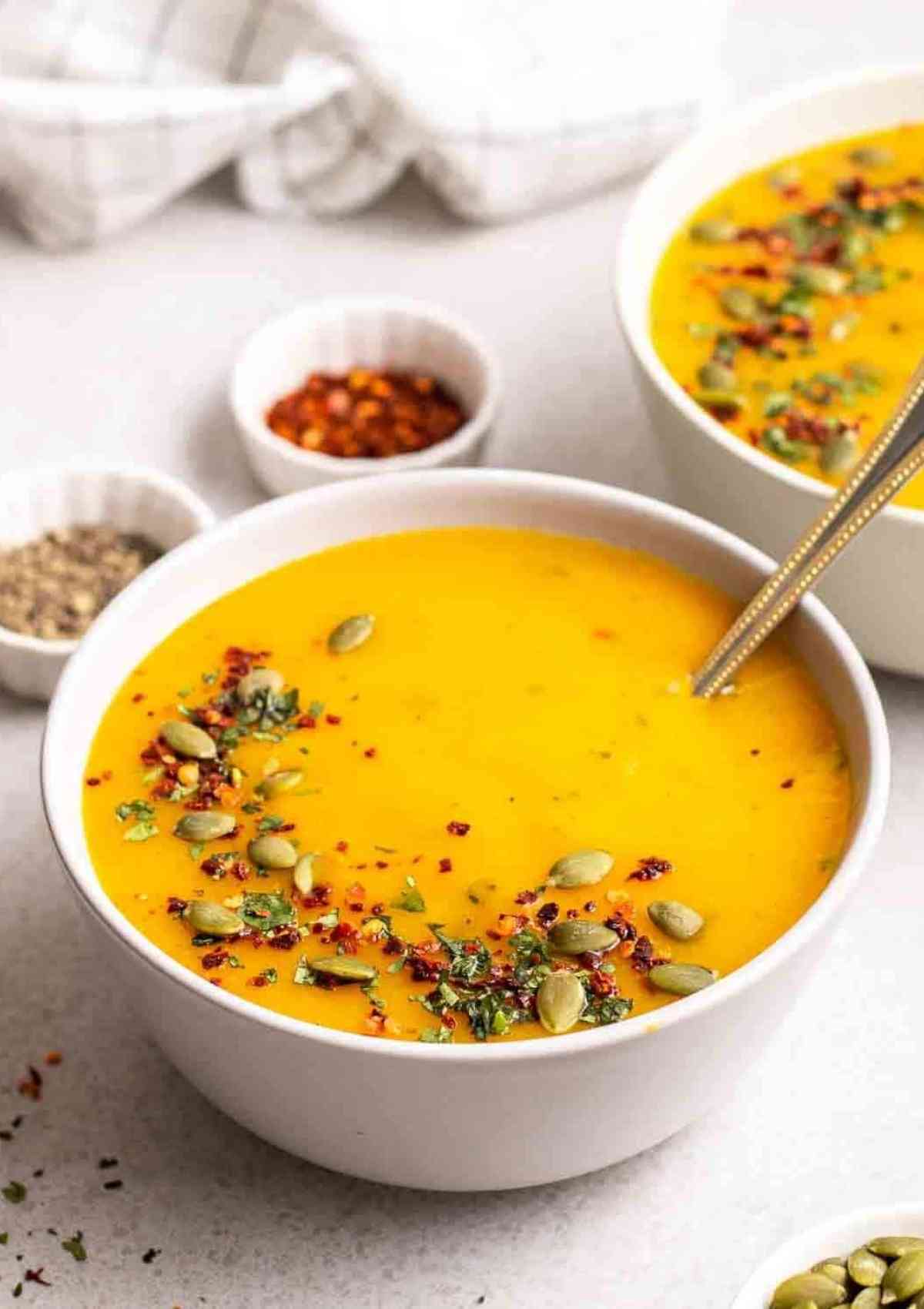 yellow color pumpkin potato soup served in white bowls