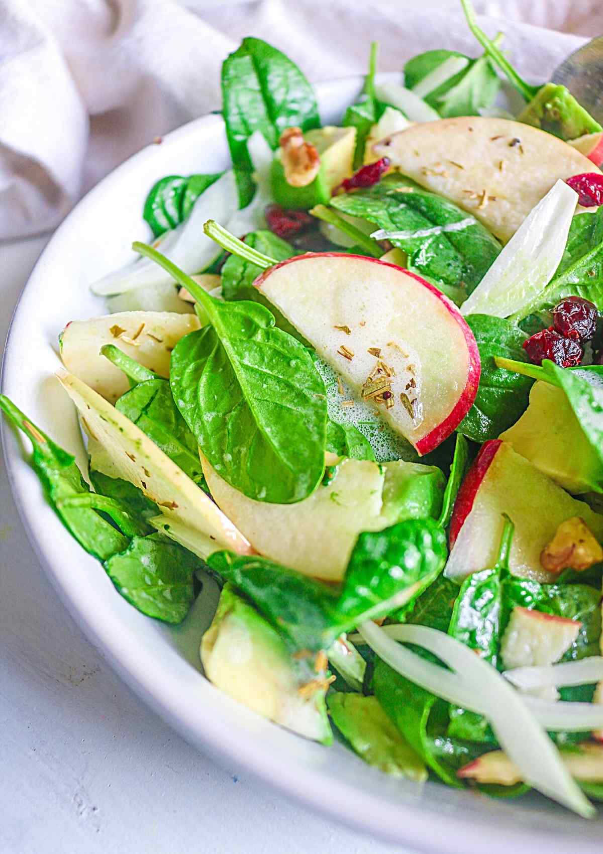 close up of spinach and thinly sliced apples and onions