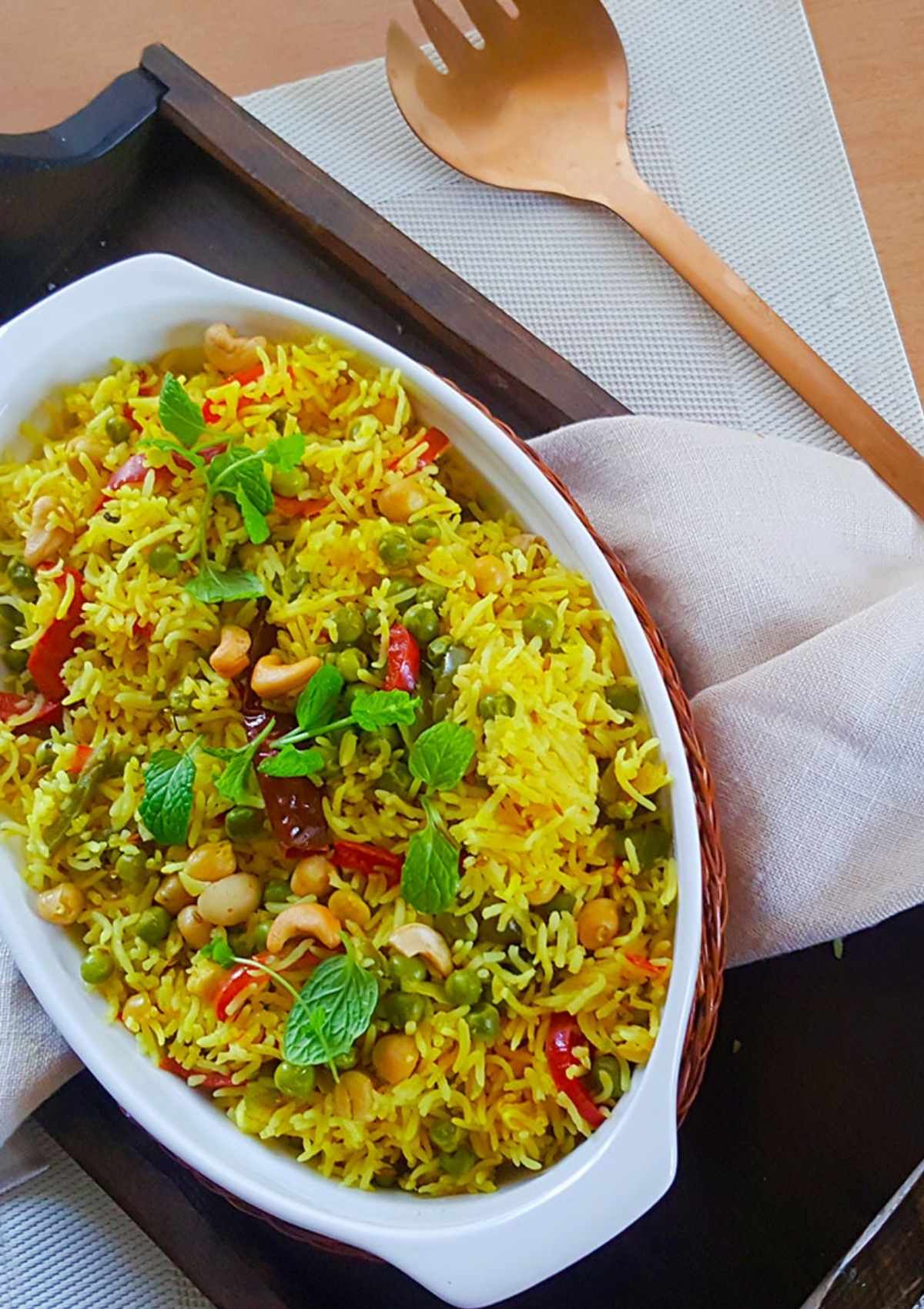 rice served in a white dish and a copper spoon on side