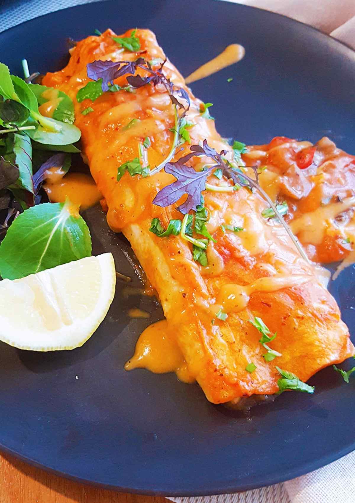 creamy mushroom enchiladas served in black plate closeup view