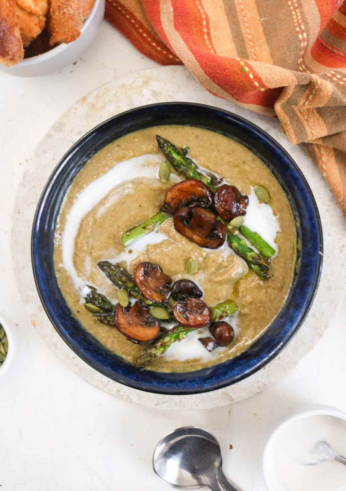 creamy Asparagus Mushroom Soup served in a blue bowl and orange napkin