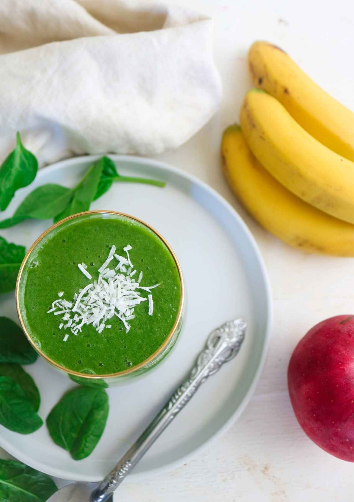 Apple banana spinach smoothie topped with coconut flakes