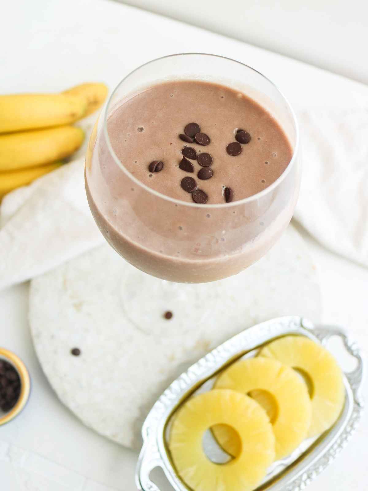  chocolate pineapple smoothie in a glass with pineapple slices on side