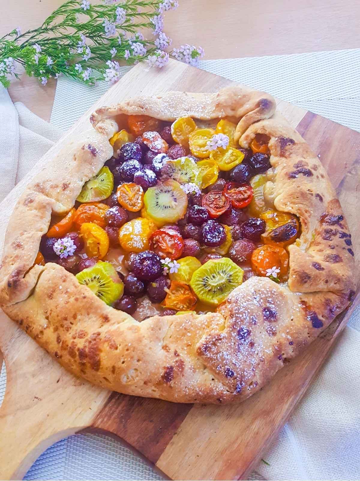full vegan galette placed on a wooden board and flowers on background