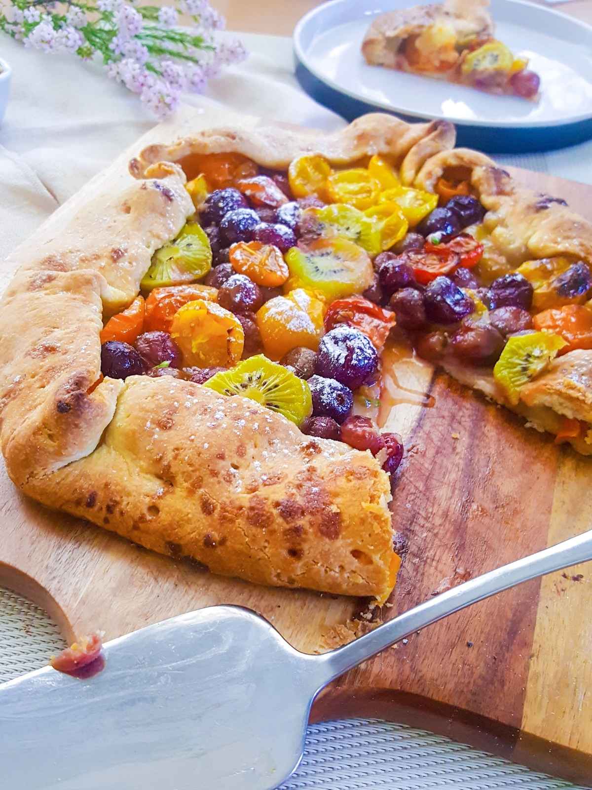 vegan galette placed on a wooden board with a slice served on a plate on the background