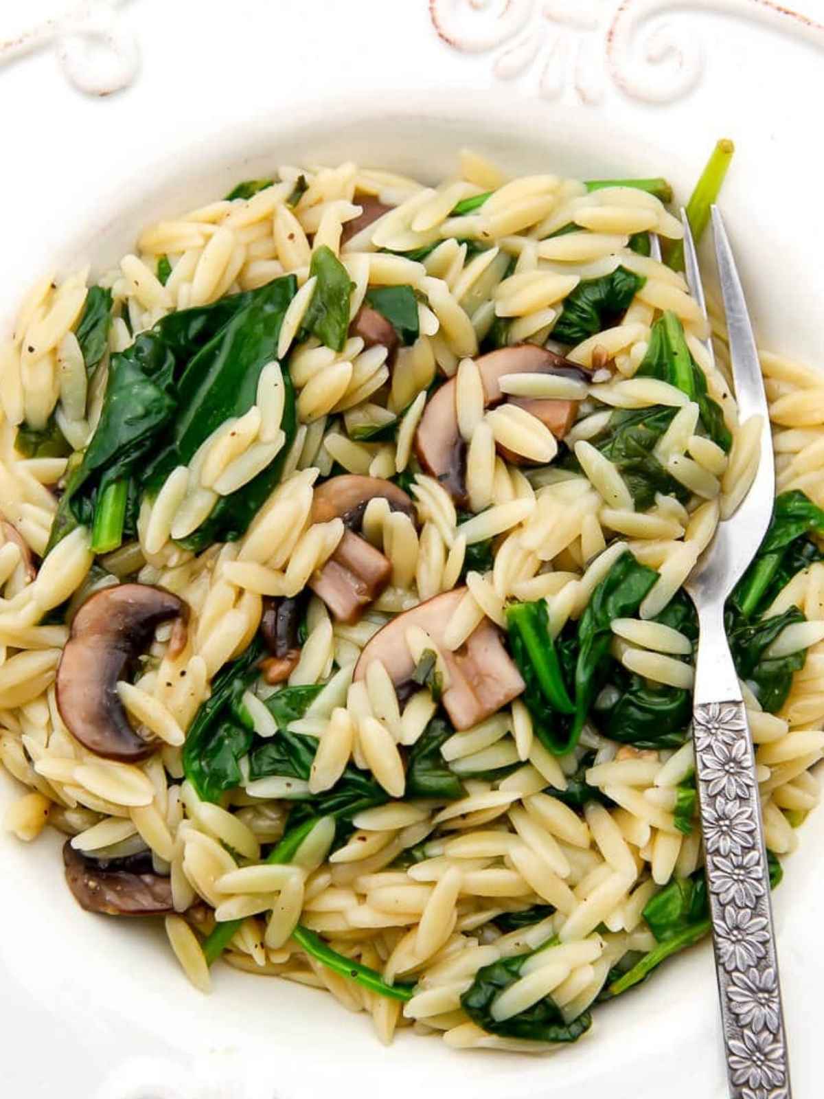 Orzo Risotto served in a white plate with a fork.