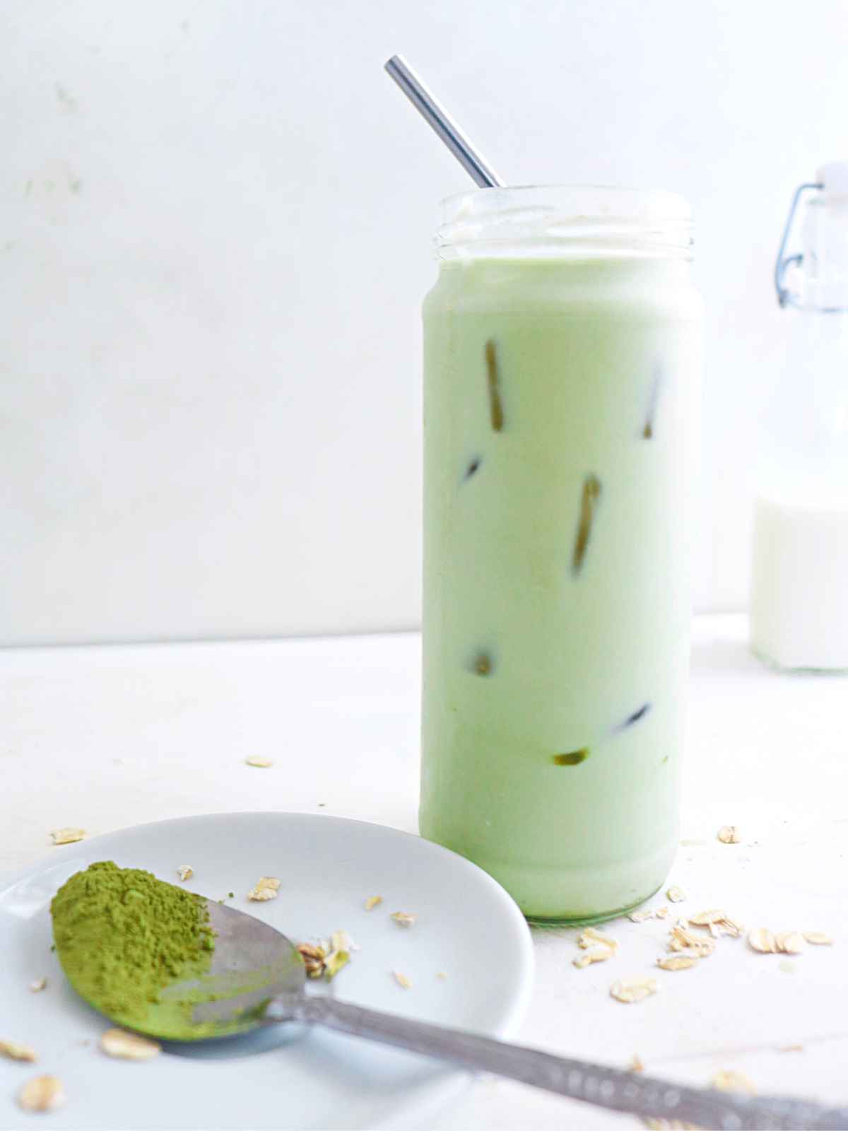 glass of matcha latte and matcha powder in silver spoon.