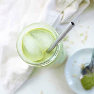 iced matcha latte in a glass with metal straw in it.