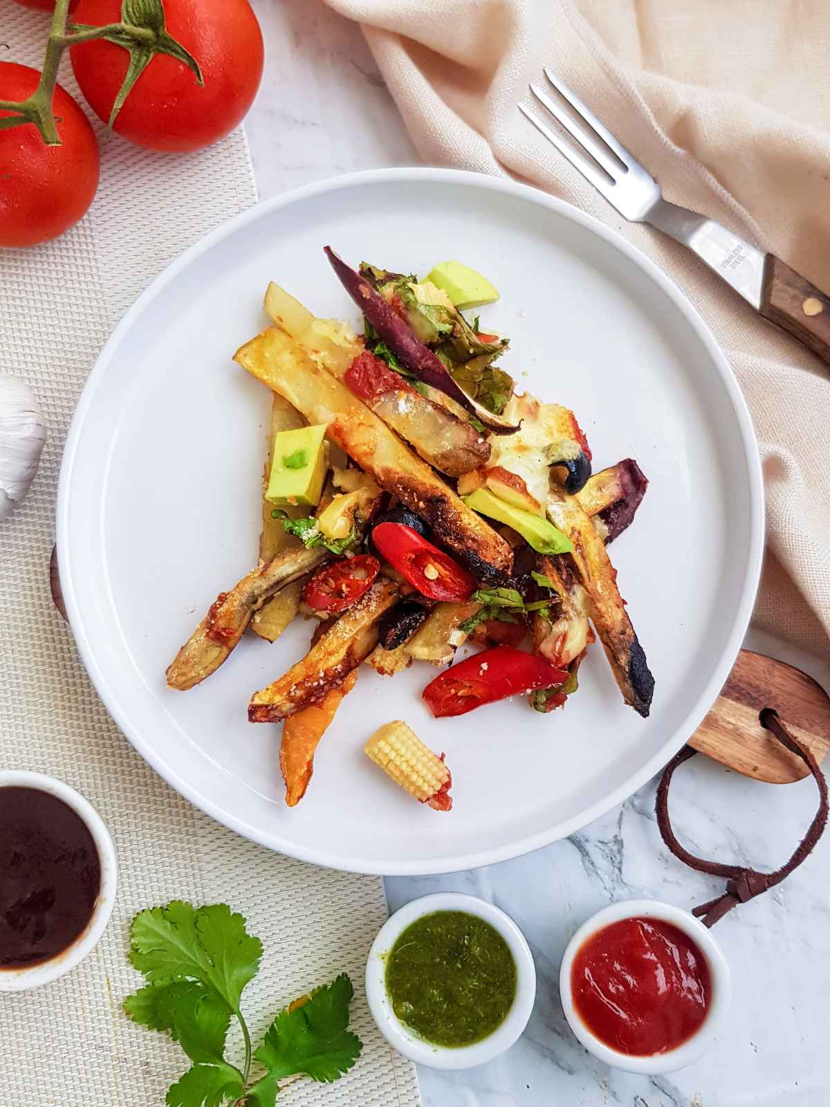 Vegan loaded served on a white plate with dipping sauces on side.