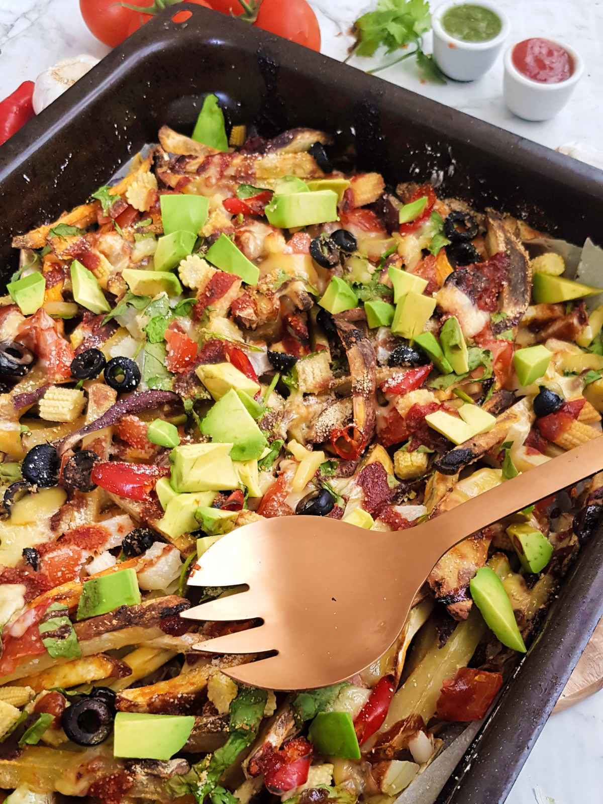 fries topped with veggies, olives and avocado.