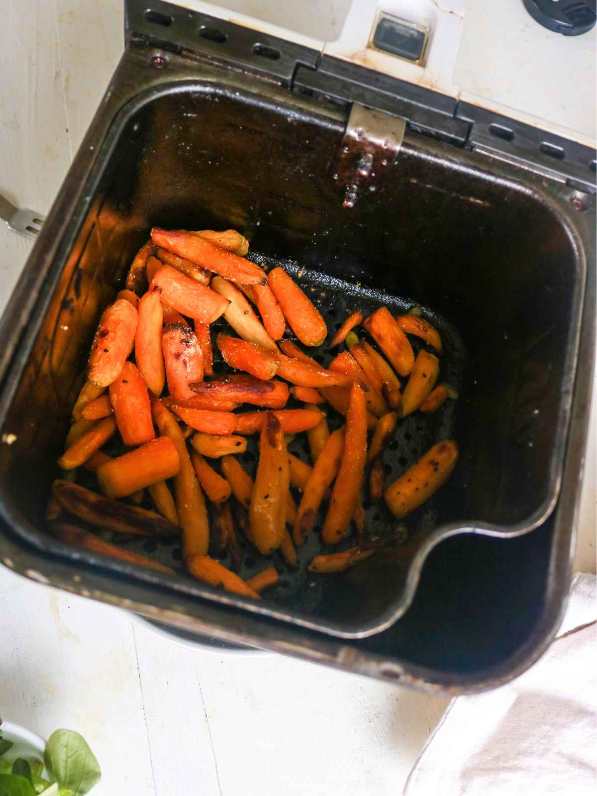 orange color Baby carrots placed in air fryer basket.