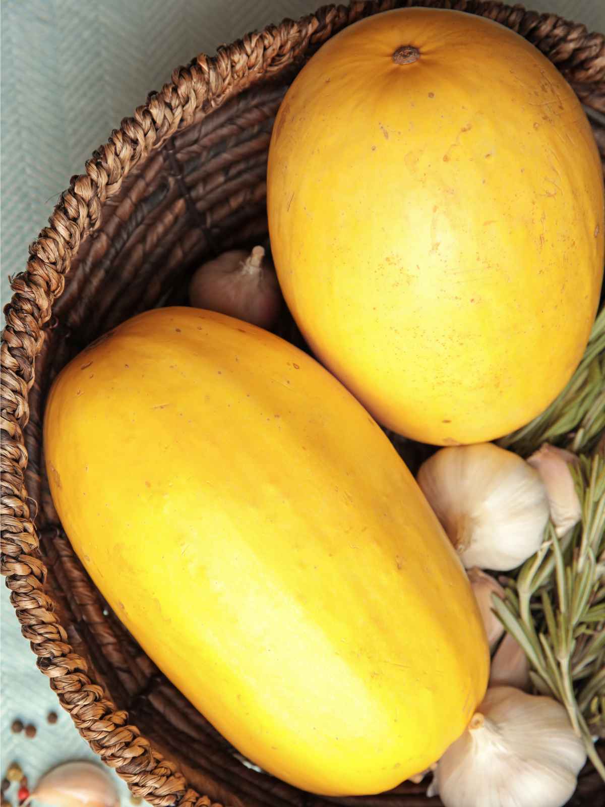 Two yellow color spaghetti squash placed in a cane basket.