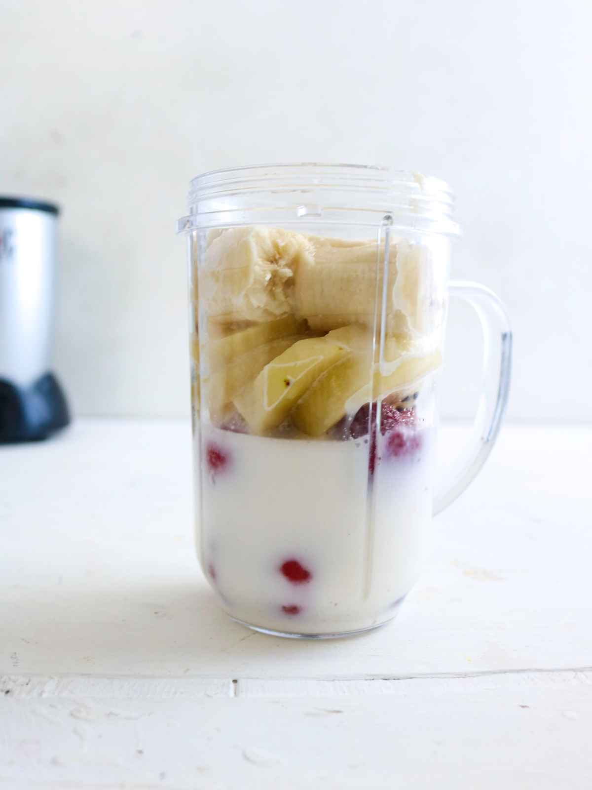 kiwi, banana, strawberry and almond milk placed in a blender jug.