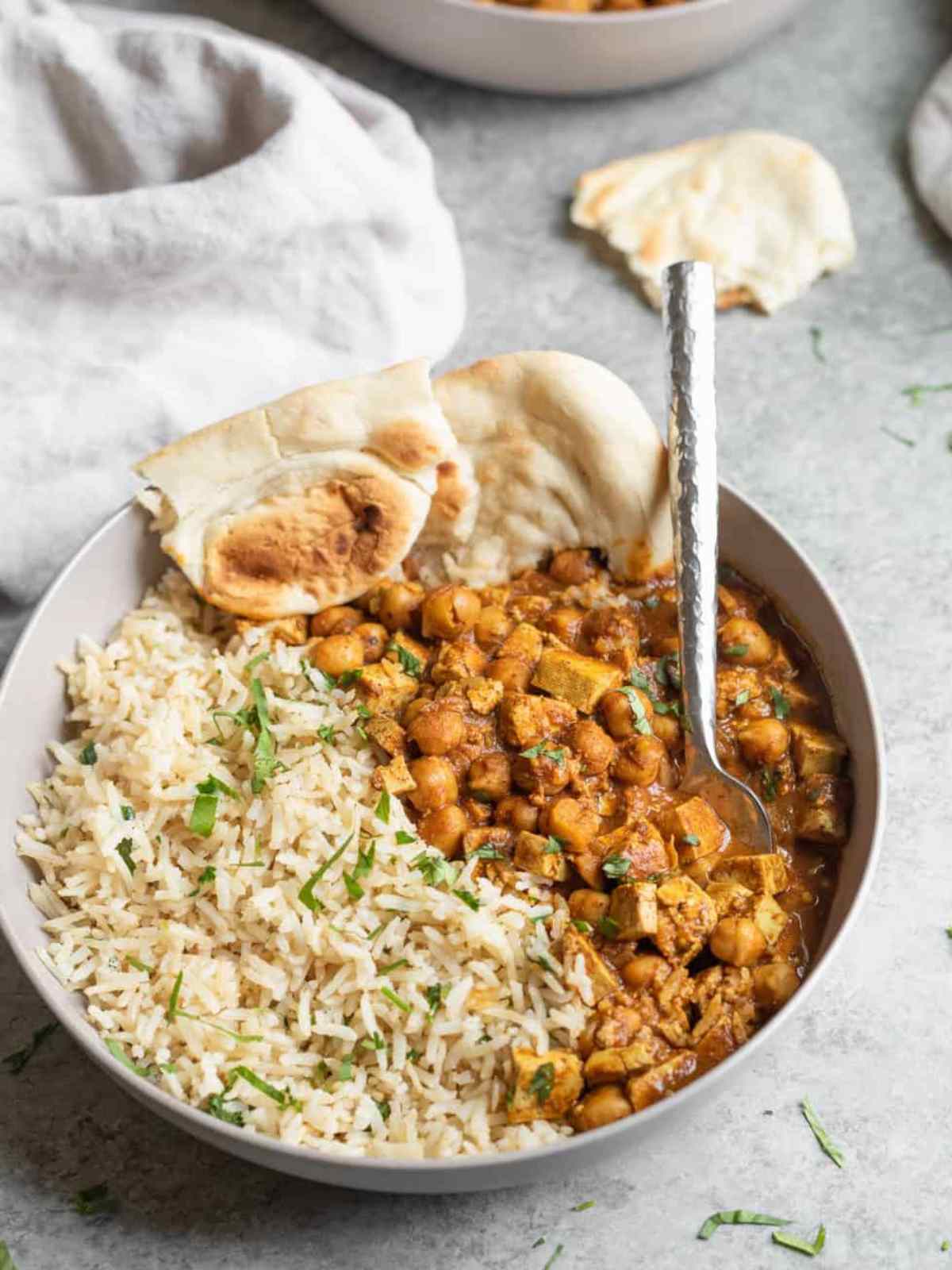 chickpeas and Tofu curry served with rice and naan in a bowl.