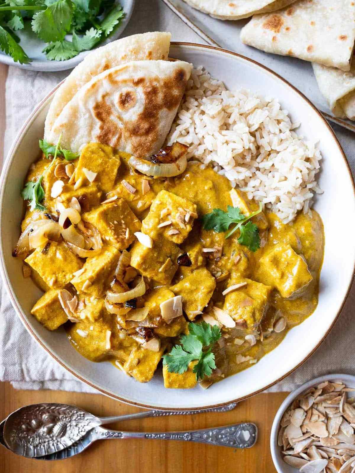 Yellow color Tofu Korma served with rice and naan.