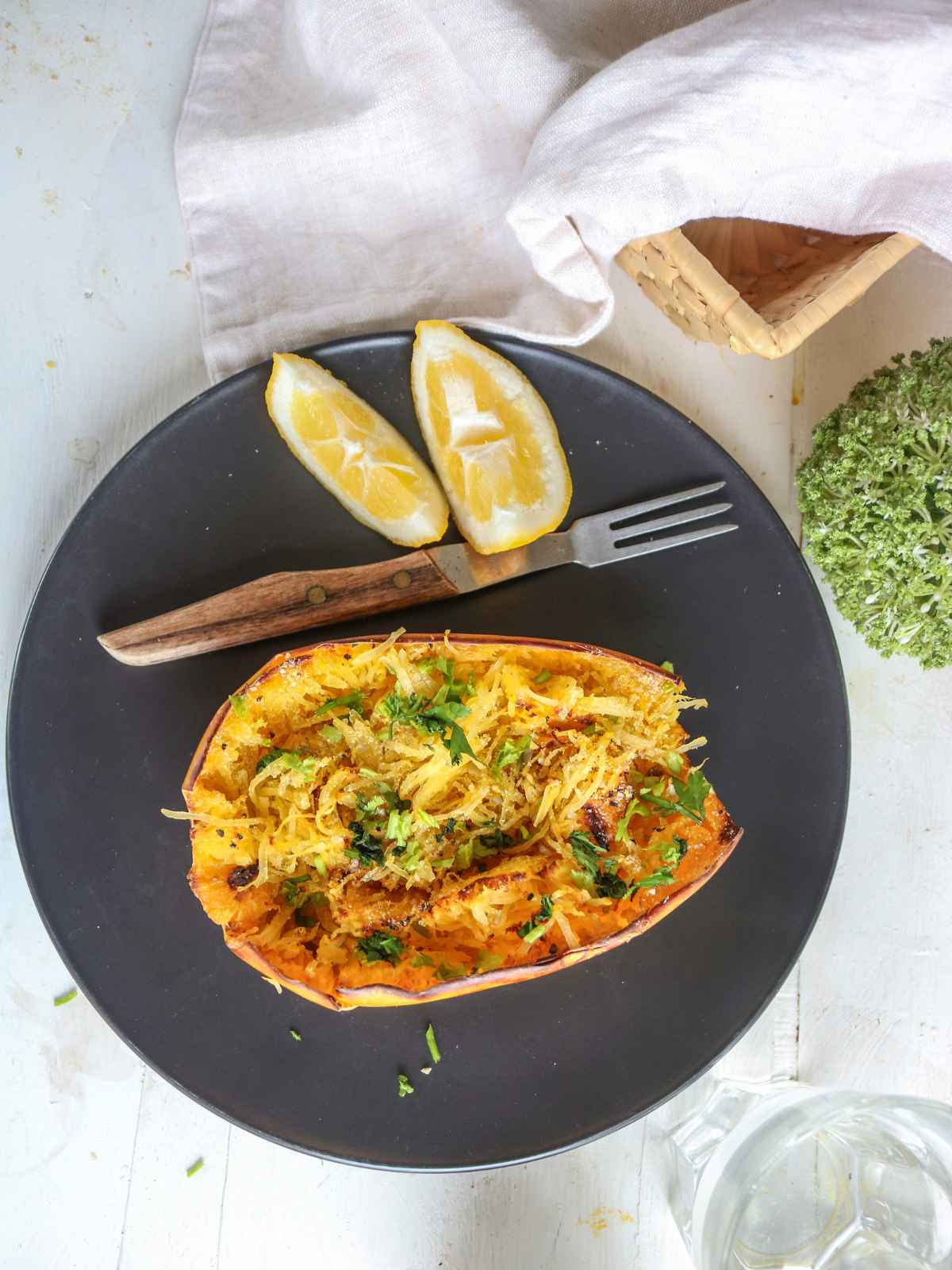 air fryer spaghetti squash served in a black plate, topped with green herbs.