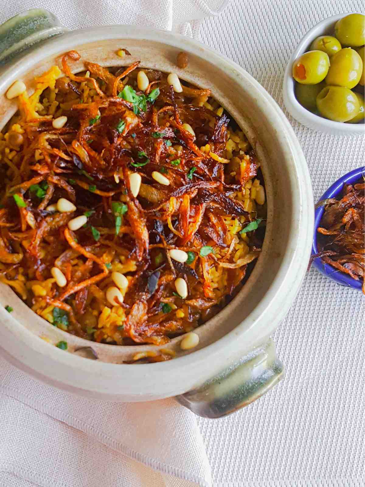 Mujadara served in a bowl topped with caramelized onions and pine nuts.