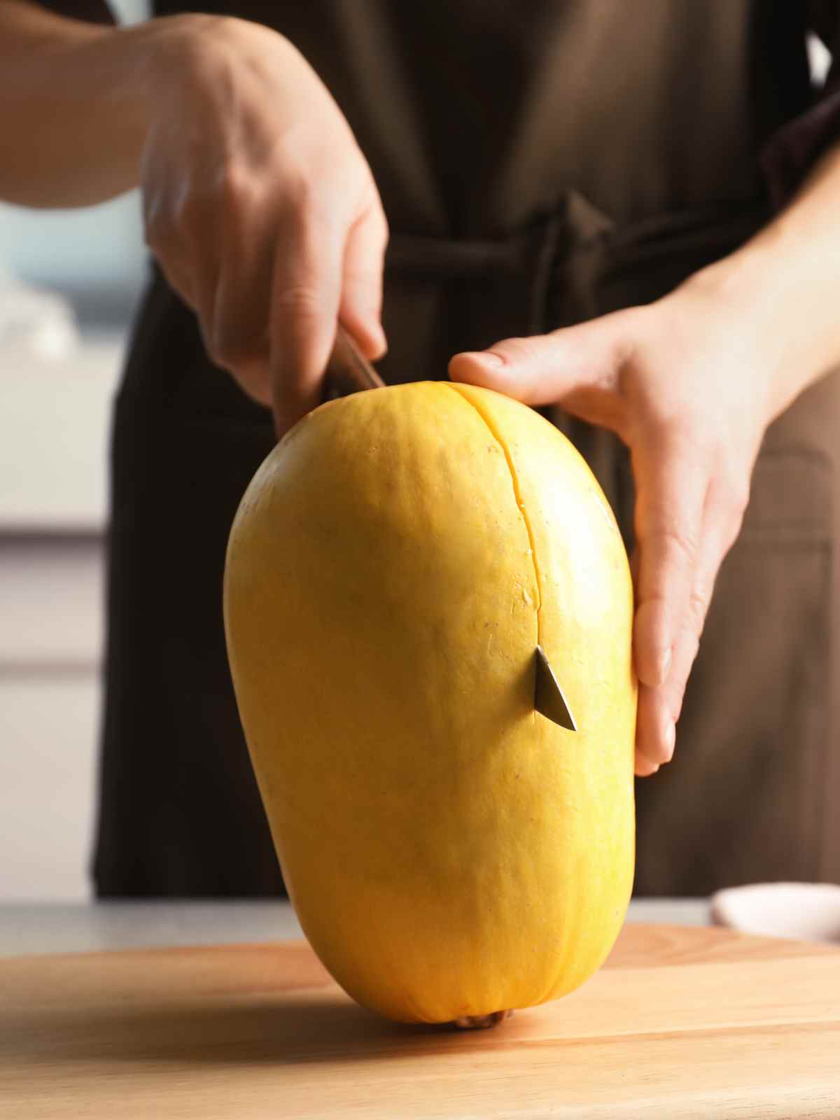 Cutting a spaghetti squash with chef knife.