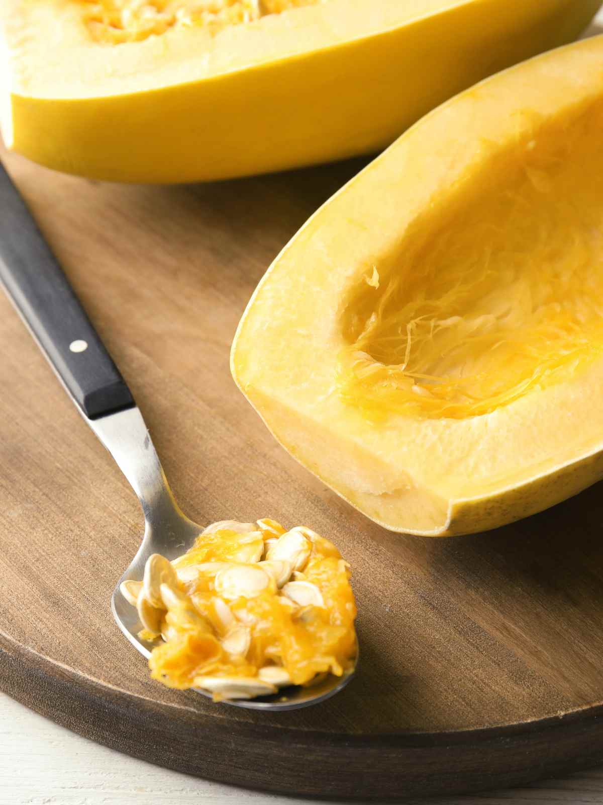 halved spaghetti squash and seeds in spoon.