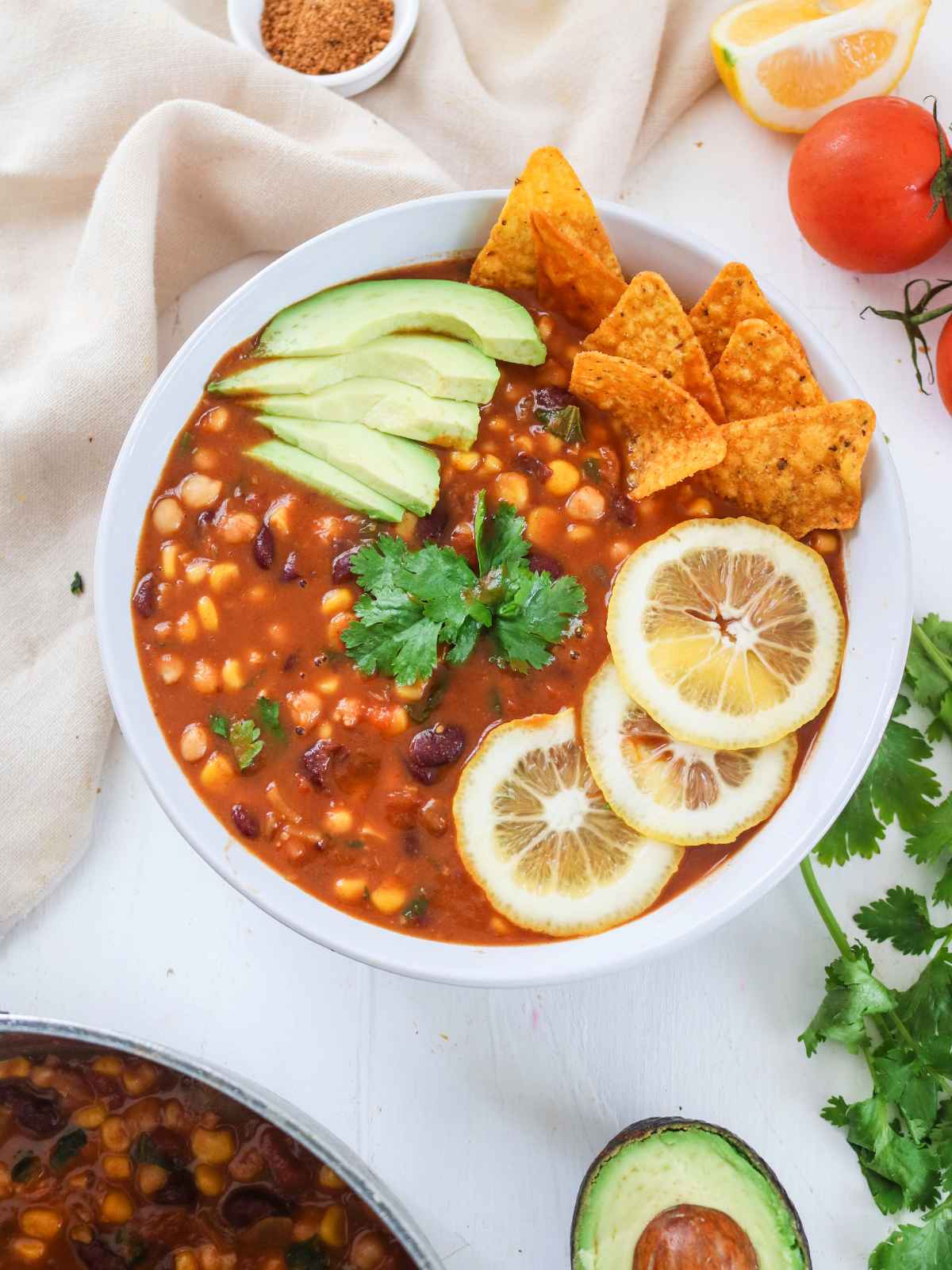 Taco Soup served in a white bowl garnished with avocado slices, cilantro leaves and lemon wedges.