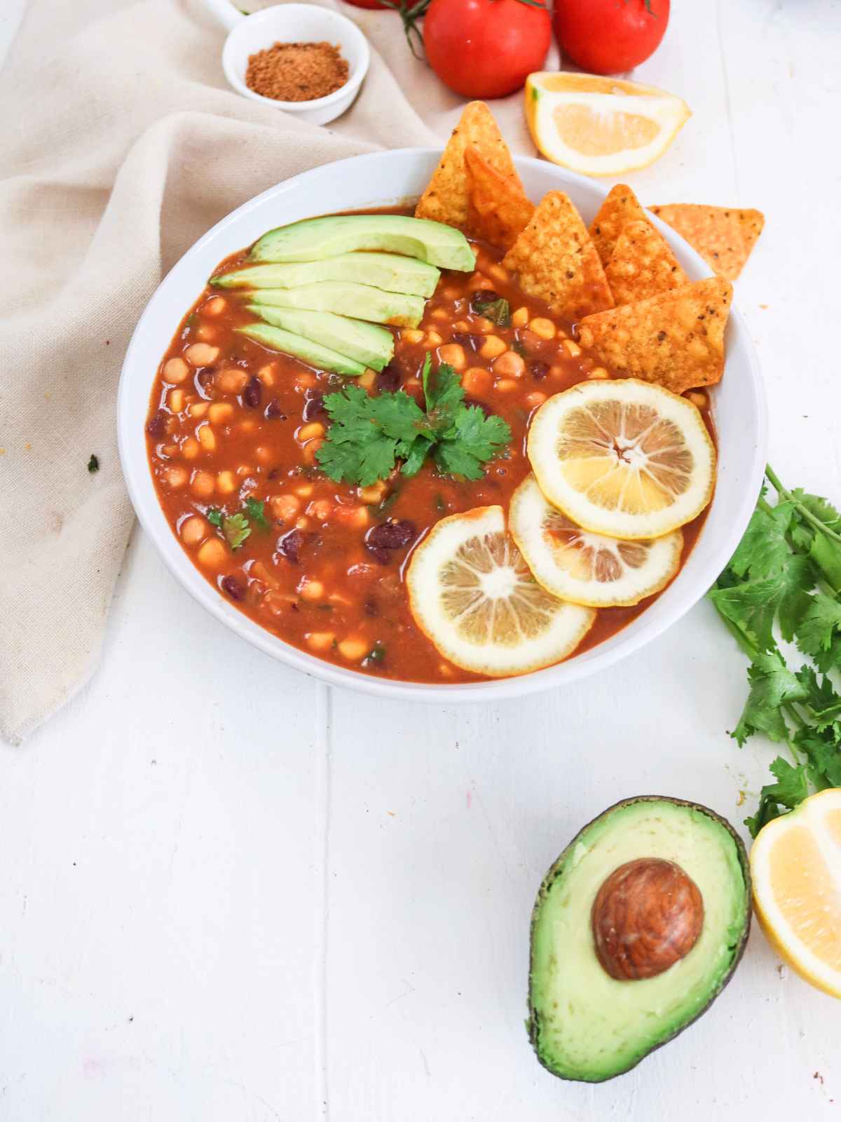 Taco Soup served in a white bowl garnished with avocado slices, cilantro leaves and lemon wedges.