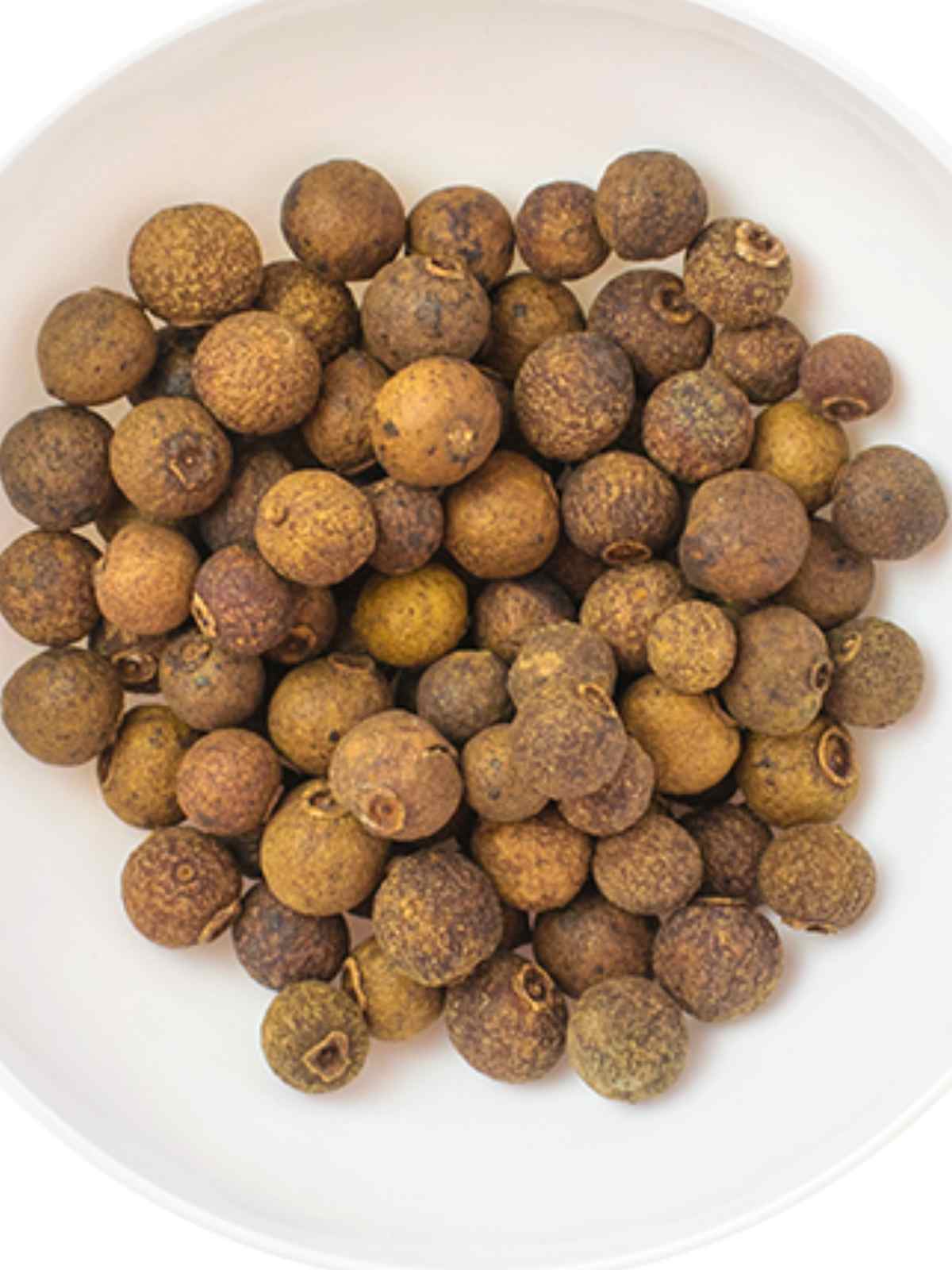 Whole all spice in a white plate.