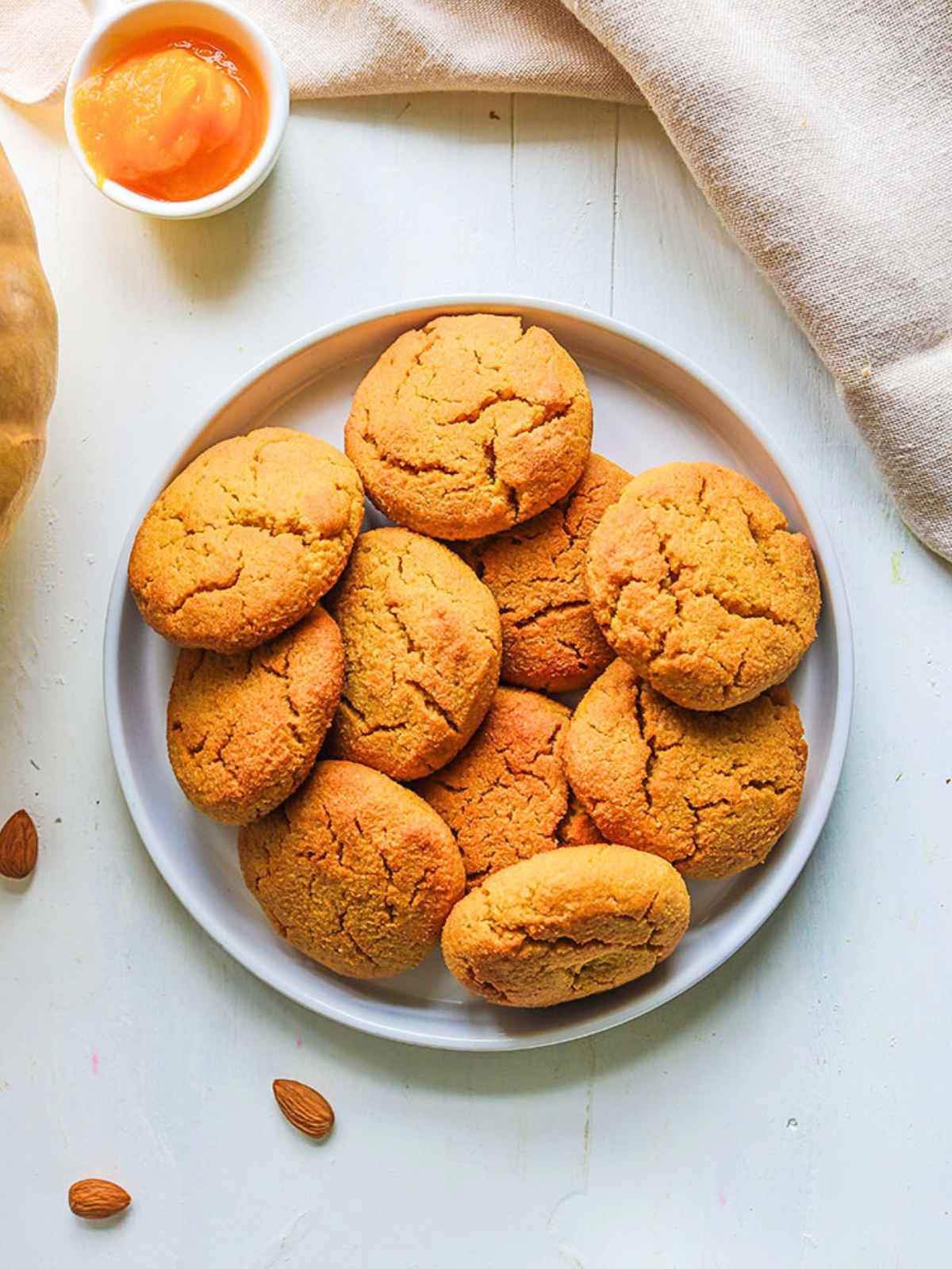 Pumpkin Almond Flour Cookies stacked in a plate. pumpkin puree in a bowl on side. 