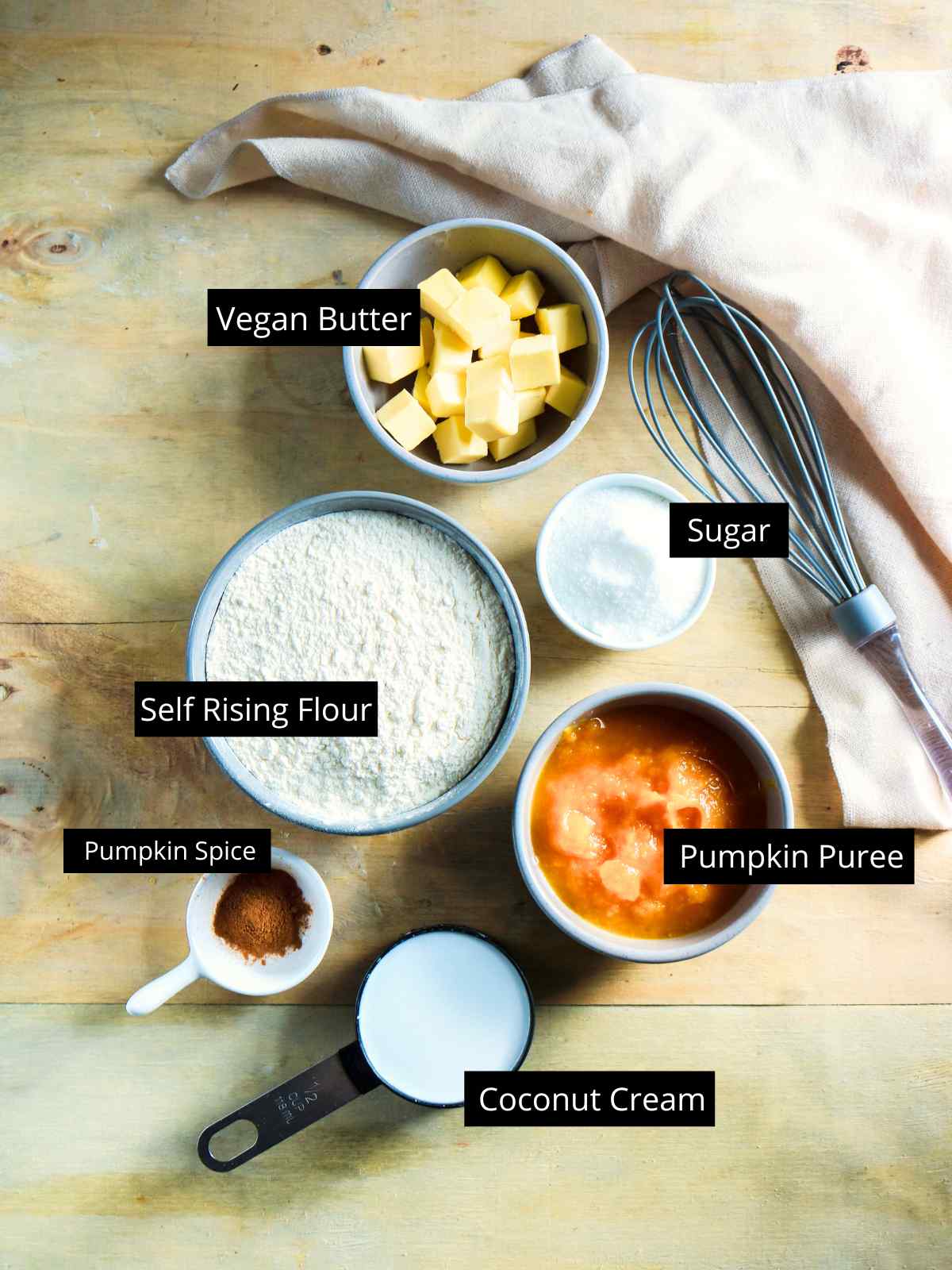 Ingredients to make eggless pumpkin scones placed on a wooden background.