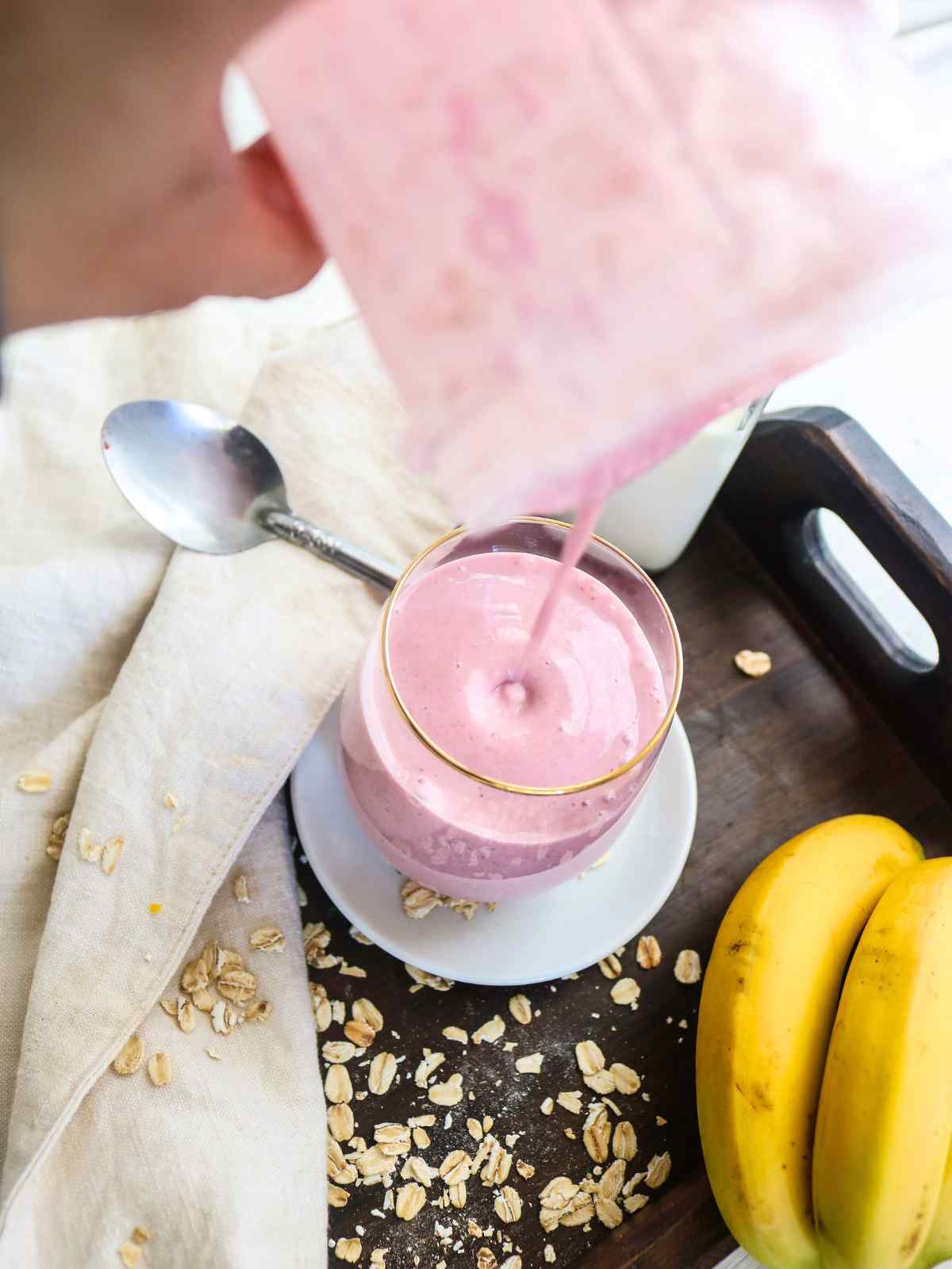 Pouring oat milk smoothie in glass jar.