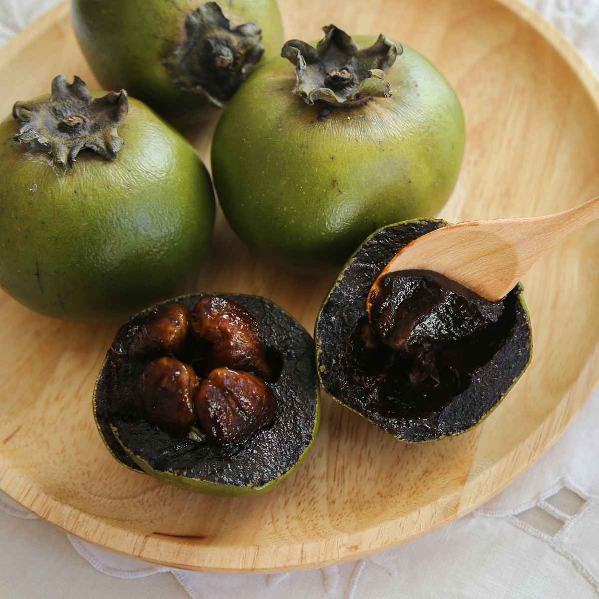 Sapote placed in a wooden plate and a half of sapote fruit.
