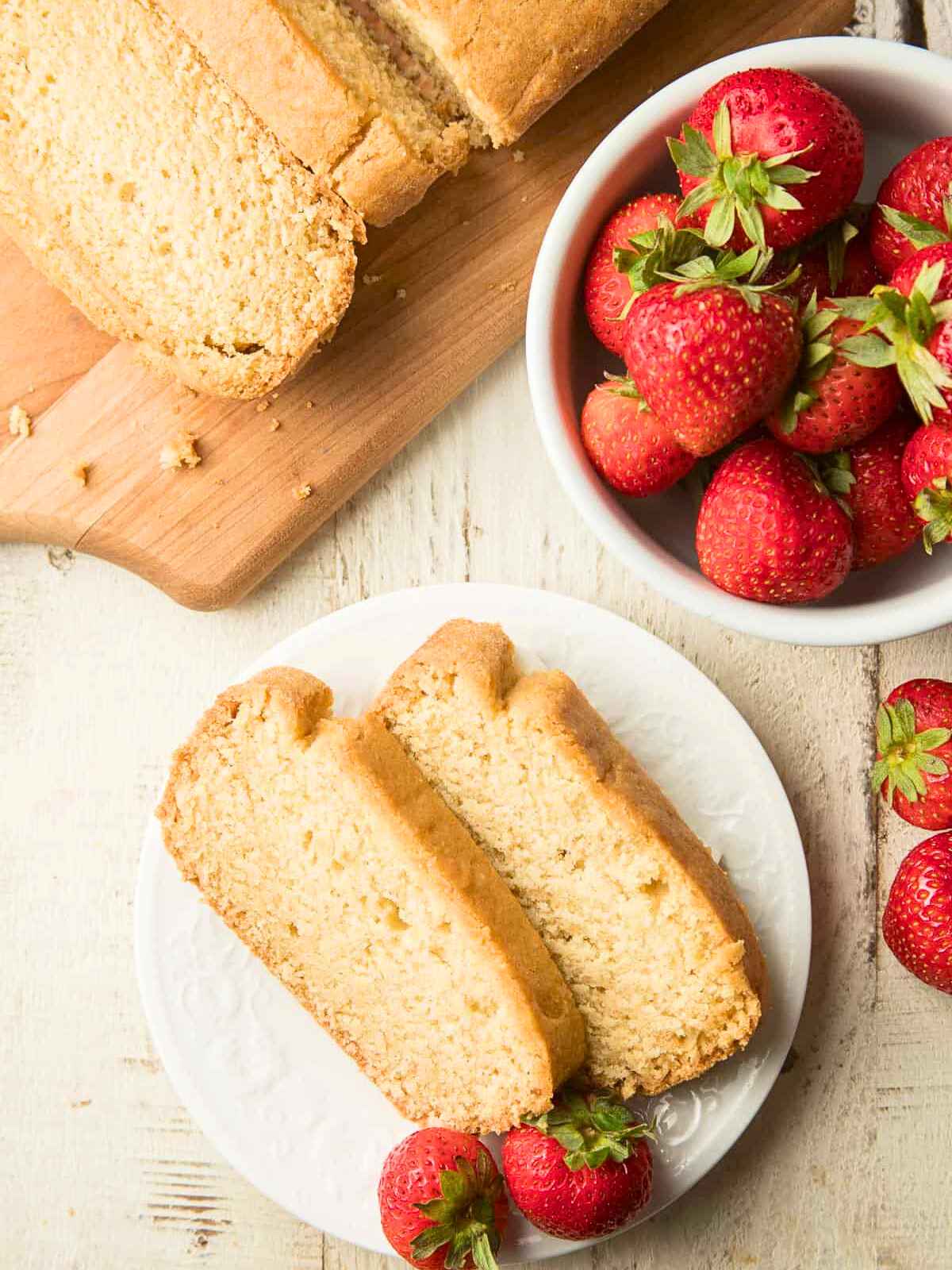 Slicing of pound cake and fresh strawberries served in a plate.