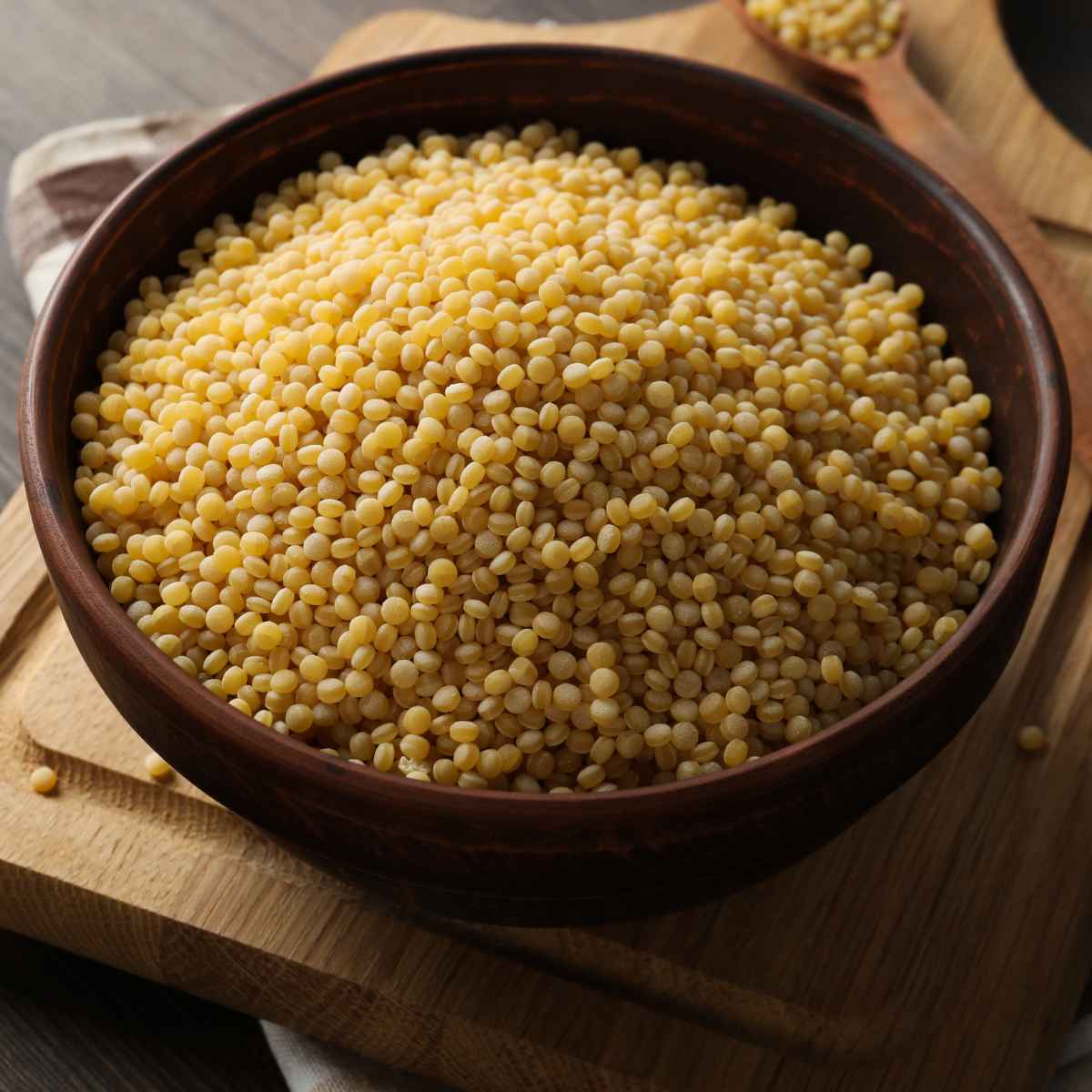 Dry couscous beads in a wooden bowl.