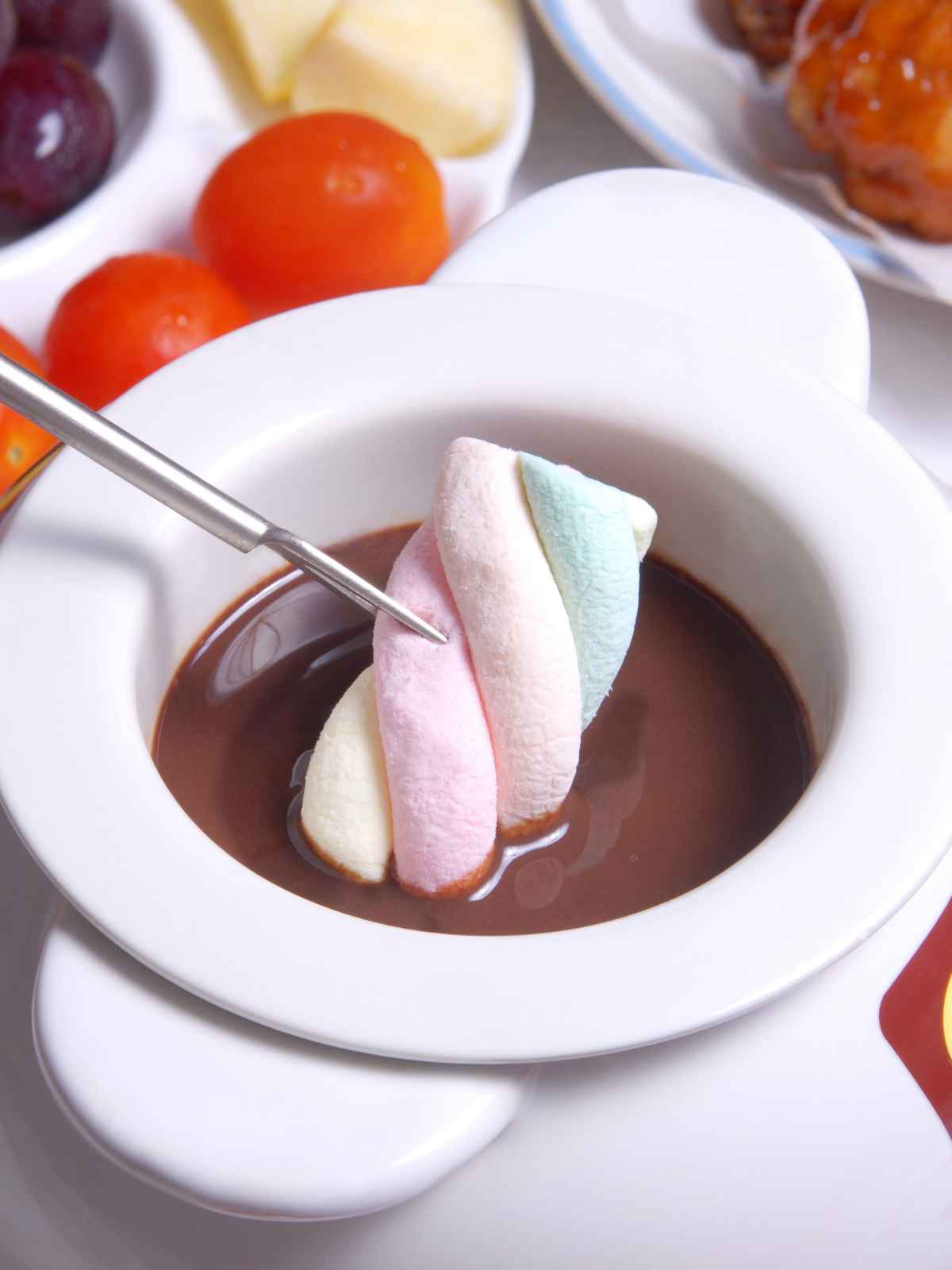 Dipping sweet marshmallow in a chocolate fondue pot. 