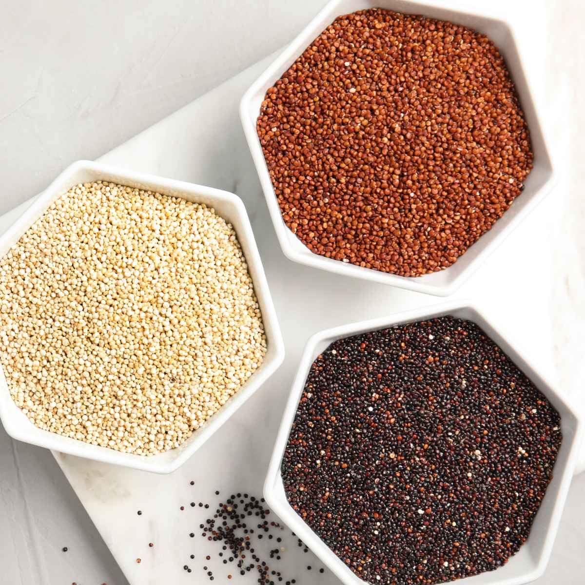 Red, black and white quinoa types placed in separate bowls.